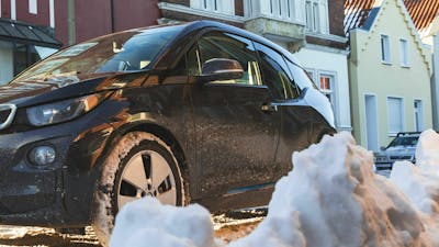 Ein Auto mit zugefrorener Tür parkt an einer verschneiten Straße