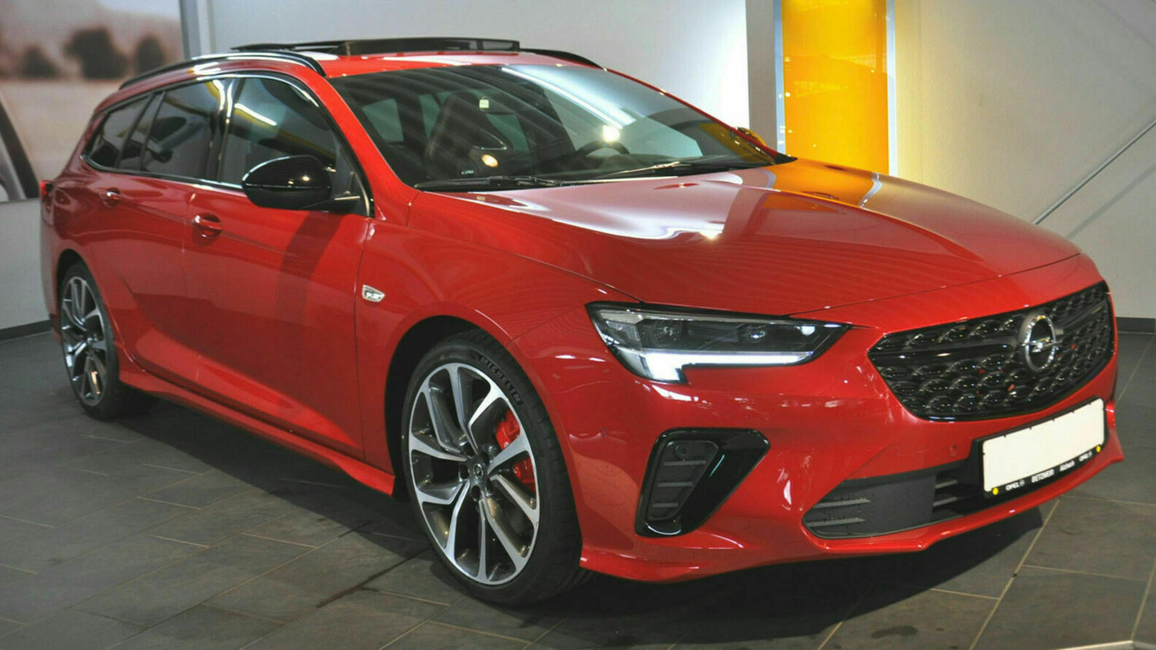 Ein roter Opel Insignia steht vor einer weißen Wand