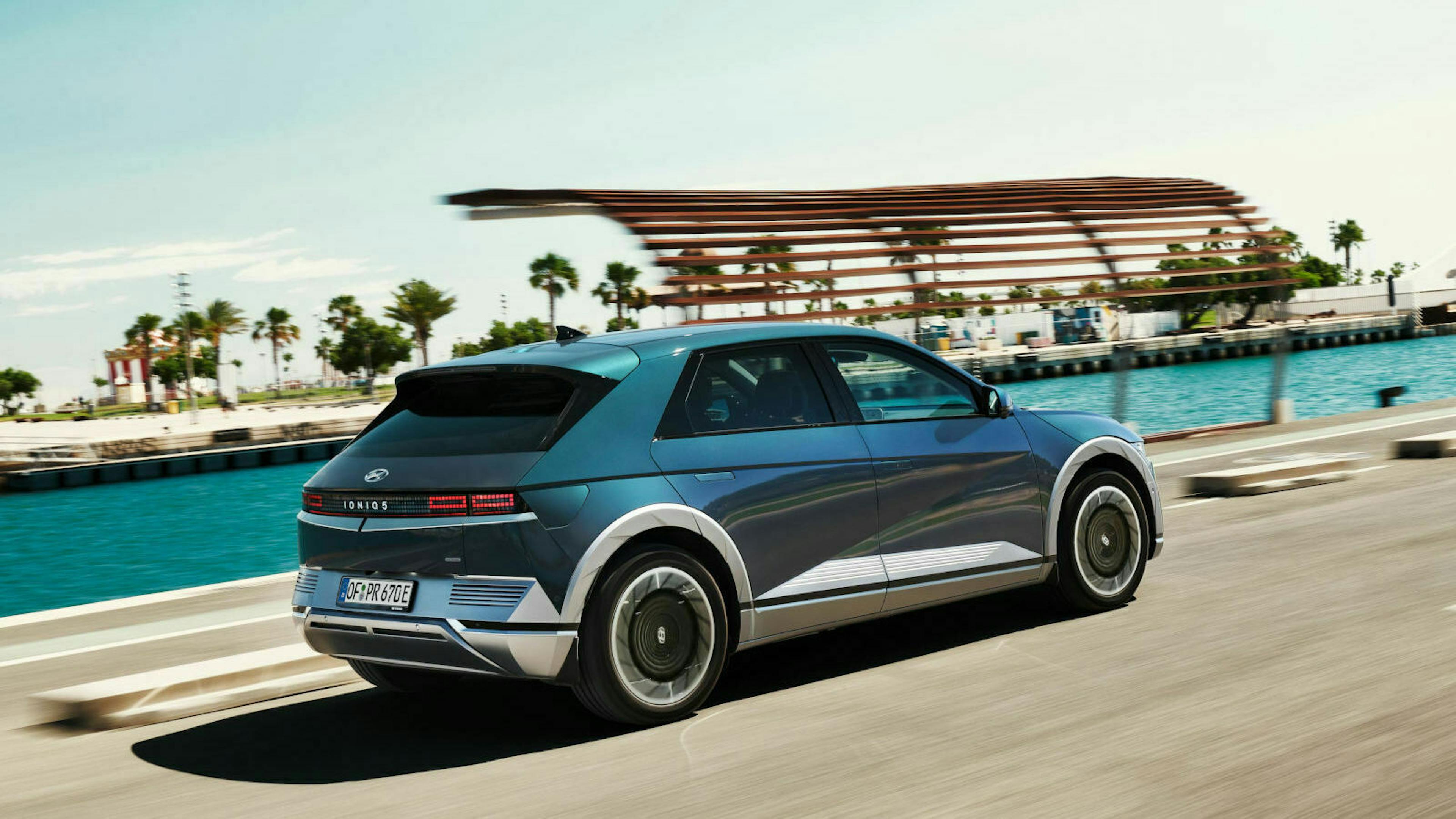 Ein blauer Hyundai Ioniq 5 fährt eine Küstenstraße entlang