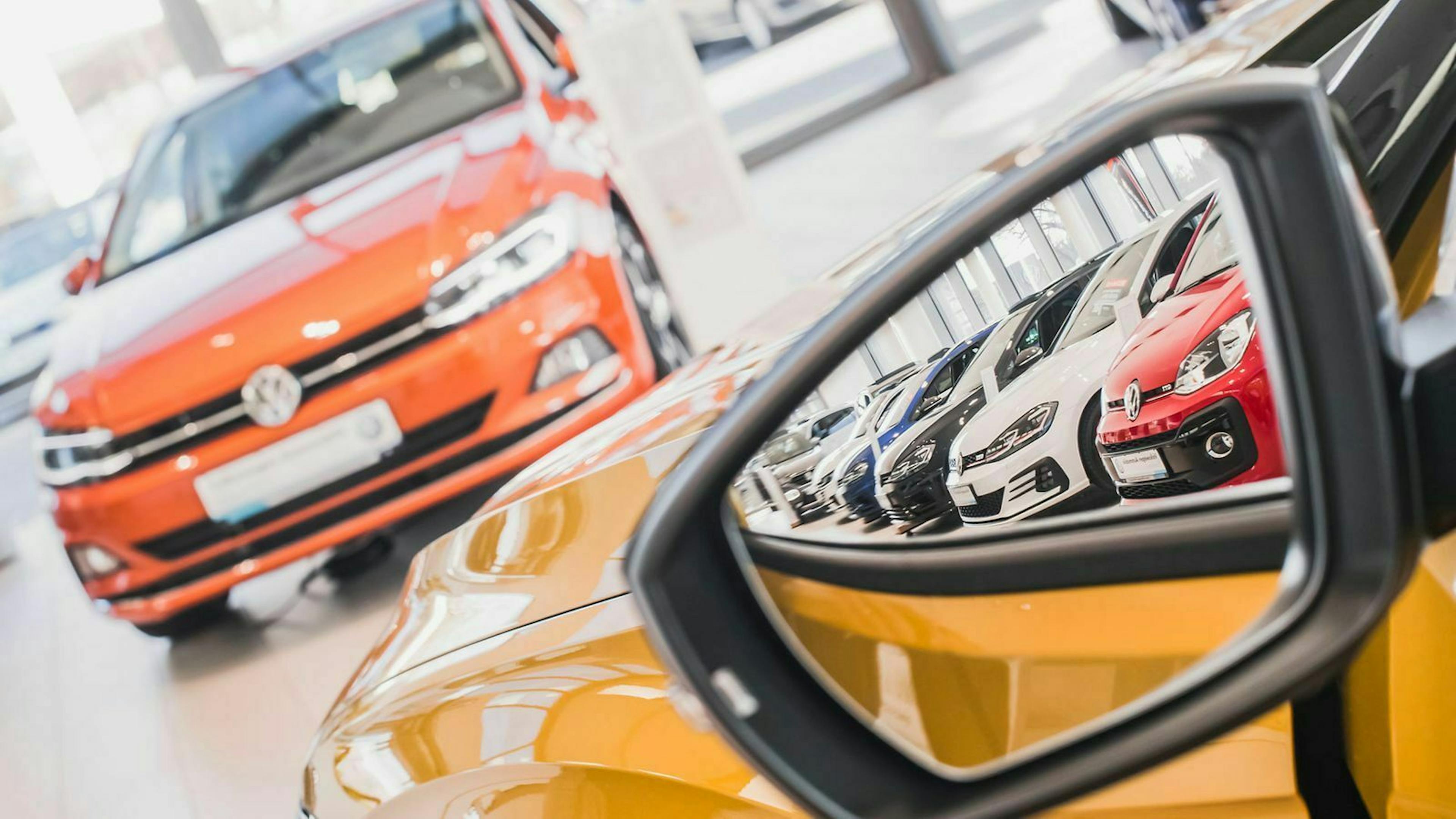 Autos stehen in einem Autohaus, draußen scheint die Sonne. 