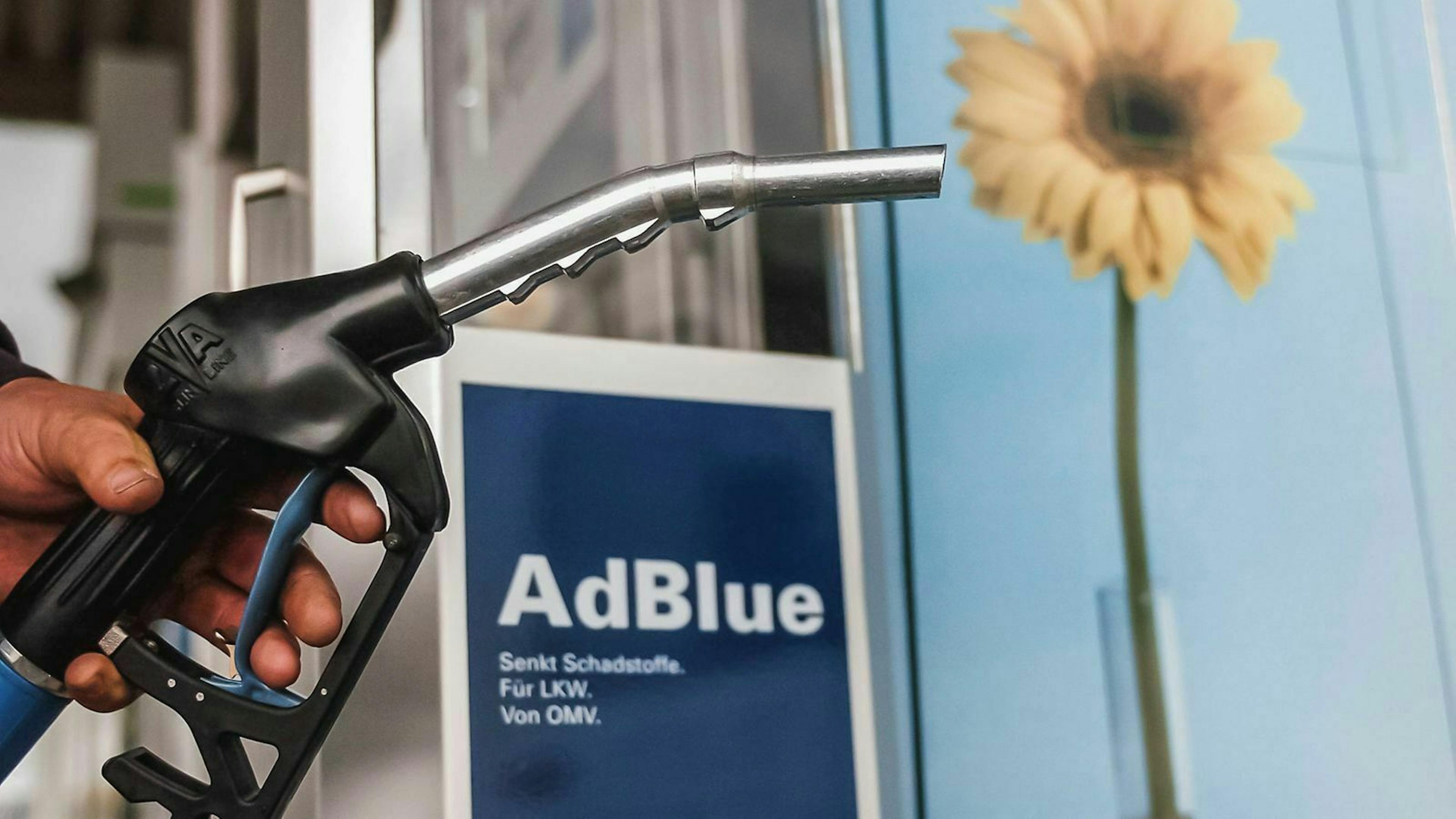 Eine Zapfpistole wird vor einen "AdBlue"-schriftzug gehalten.