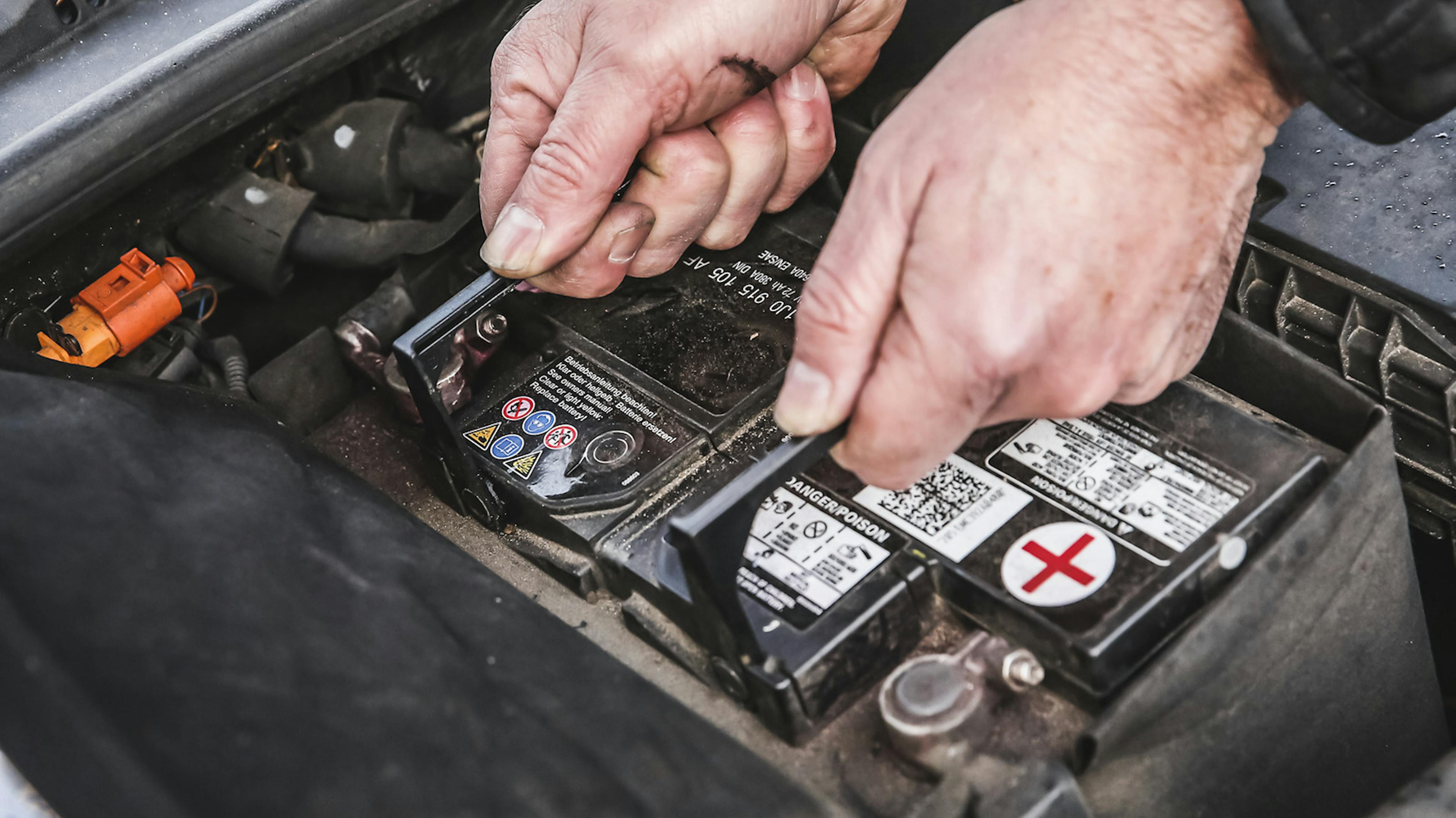 Eine Autobatterie wird aus dem Batteriefach des Autos gehoben.