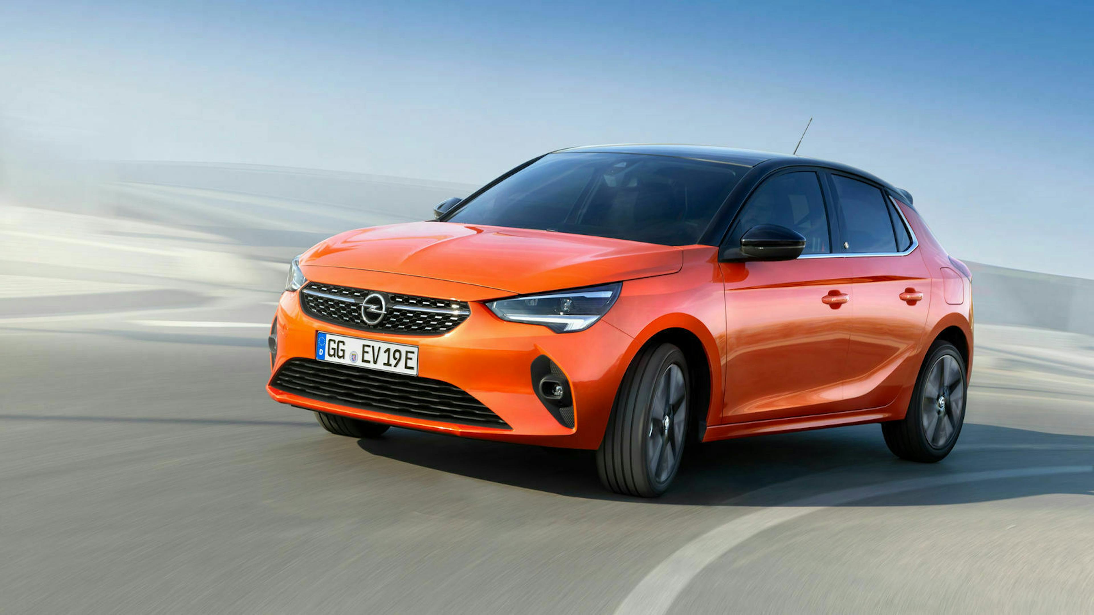 Ein orange-roter Opel Corsa-e fährt eine Straße entlang