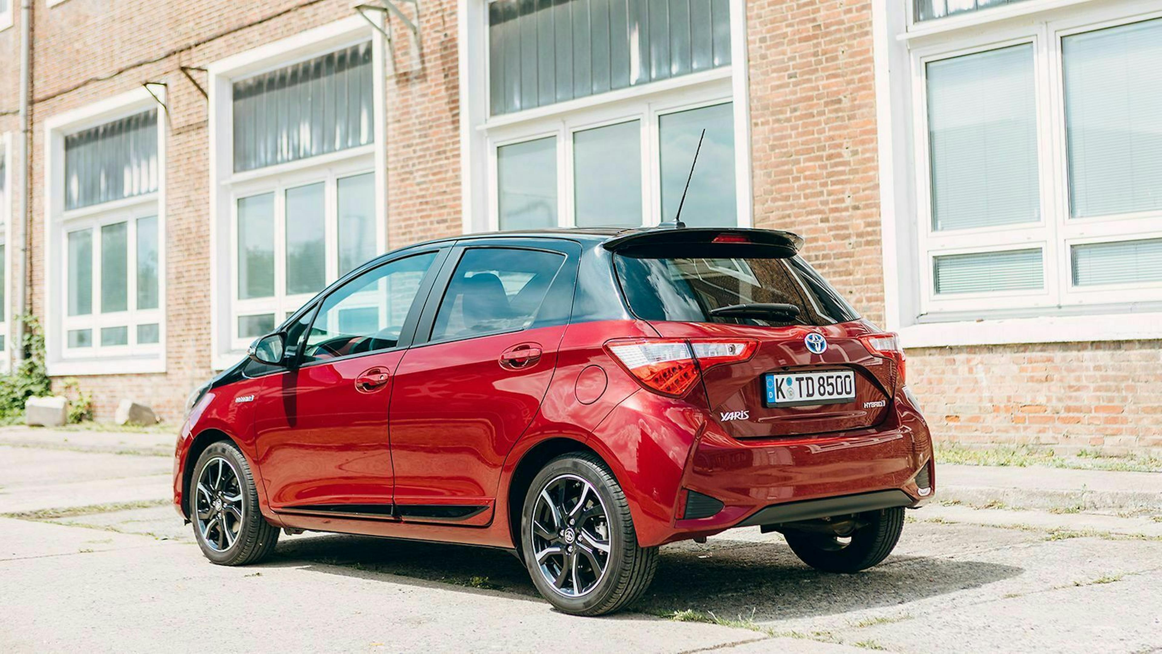 Ein roter Toyota Yaris steht vor einer Backsteinfassade.
