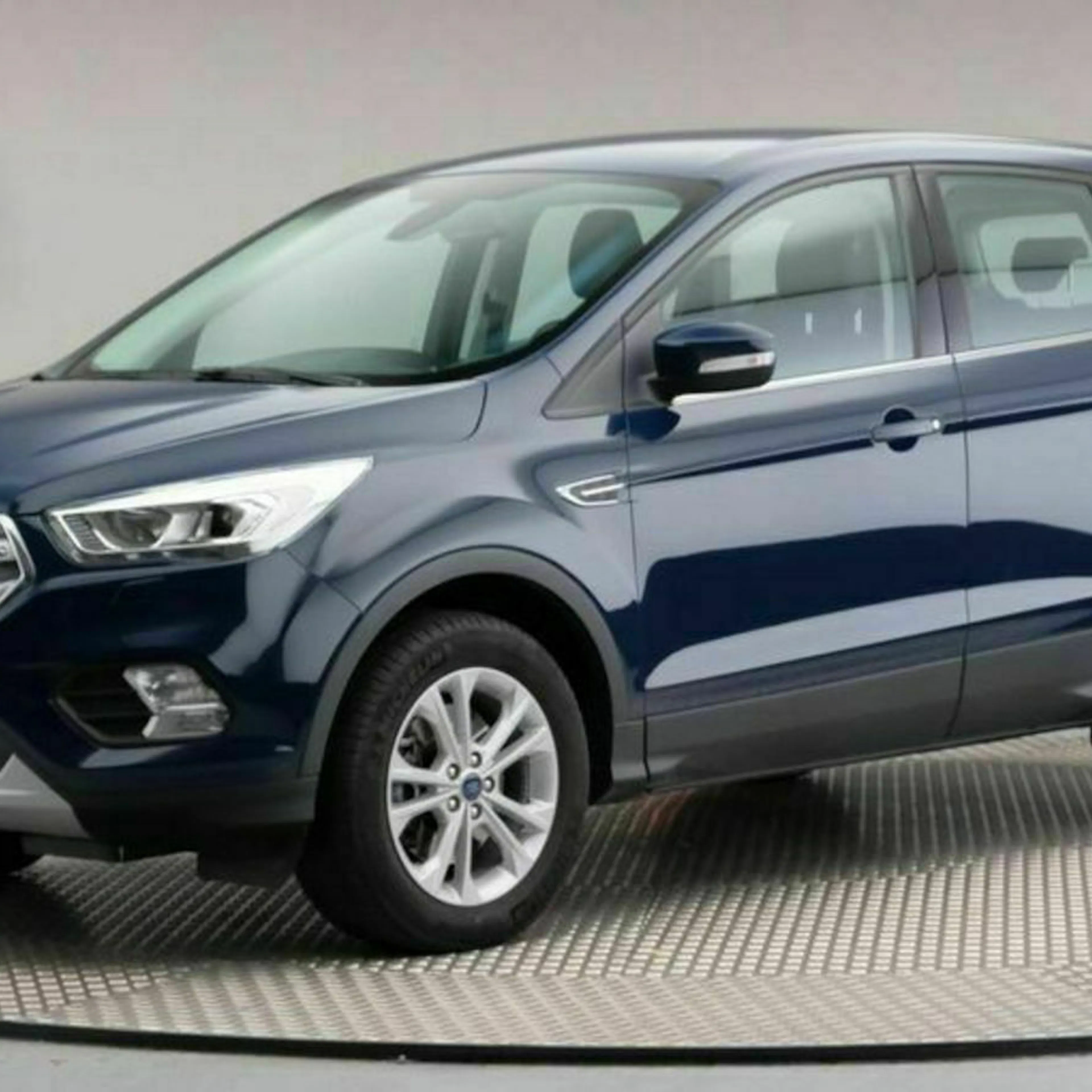 Blauer SUV steht in einem Showroom auf einem drehbaren Podest, seitliche Ansicht.