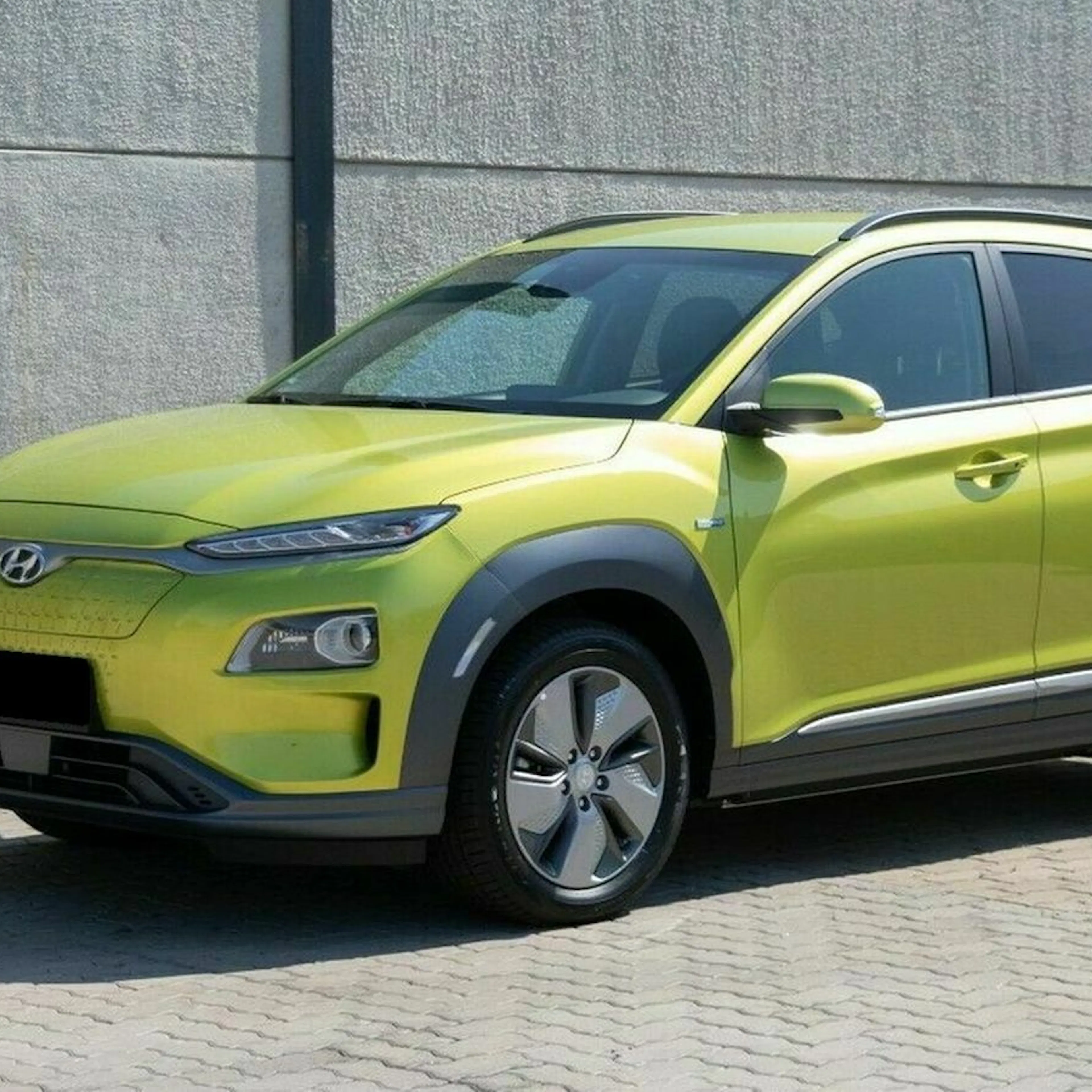 Leuchtend grünes SUV in urbaner Umgebung, schräg von vorne fotografiert. Moderner, kompakter Look mit schwarzen Verzierungen und glatten Linien.