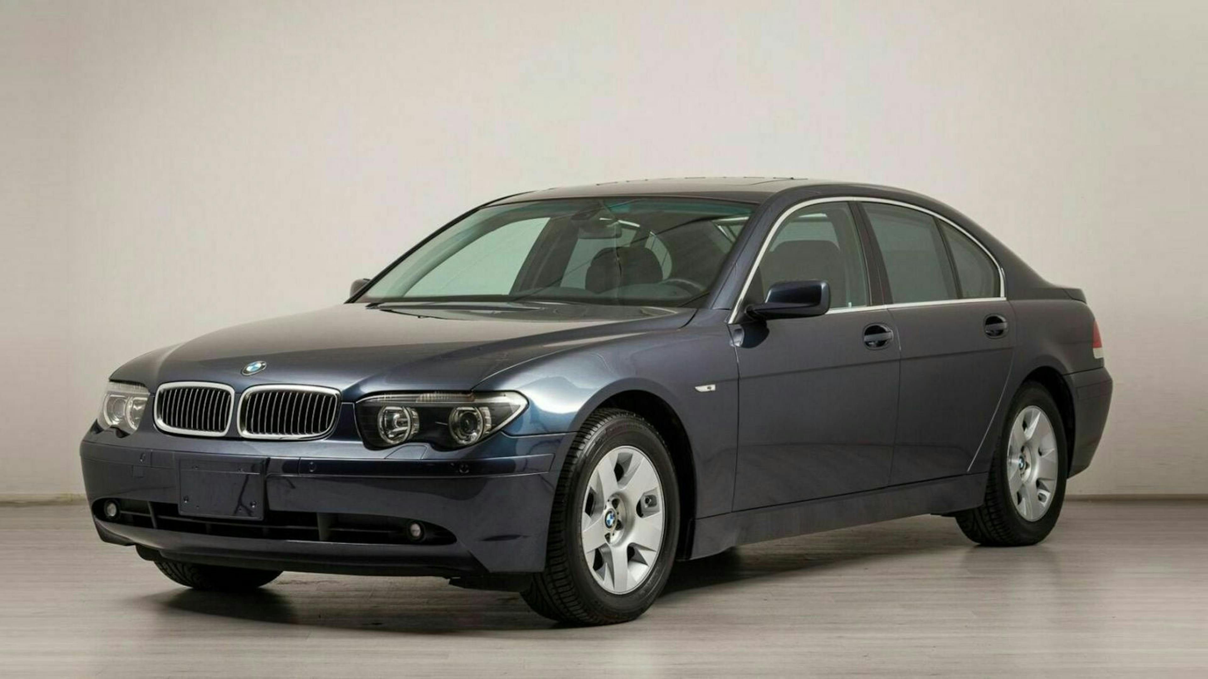 Dunkelblauer BMW 7er Limousine in einem hellen Raum, seitlich von vorne fotografiert.