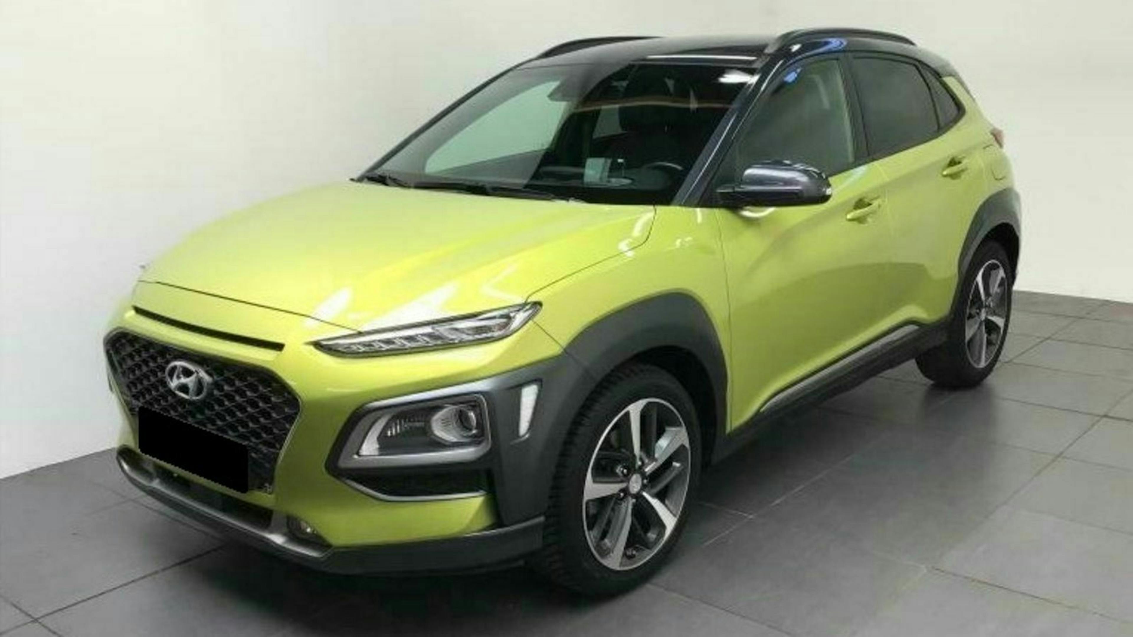 Grüner Hyundai Kona SUV in einem Showroom, schräg von vorne fotografiert. Modernes Design mit schwarzen und silbernen Akzenten.