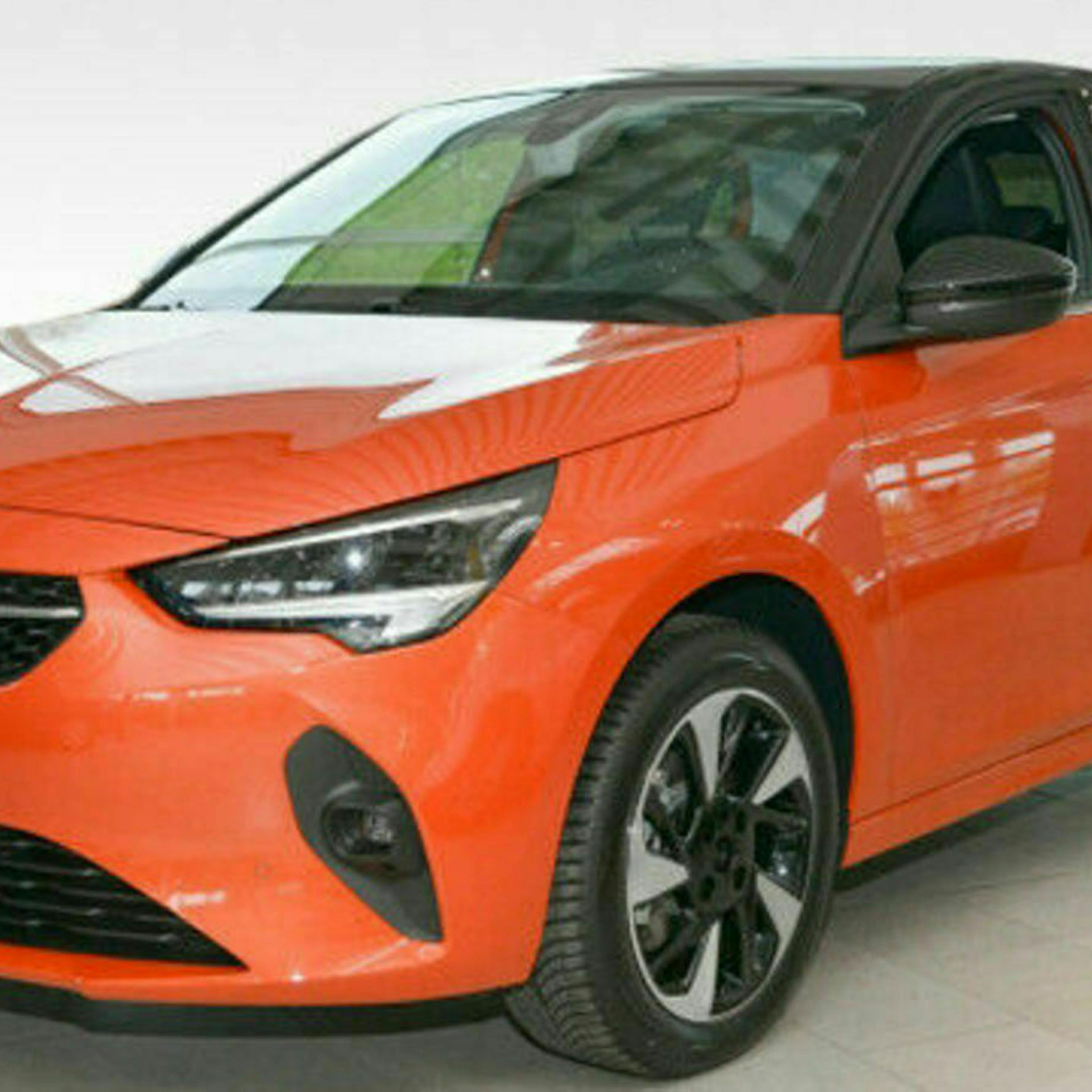 Ein orange-roter Opel Corsa-e steht in einem hellen Raum.