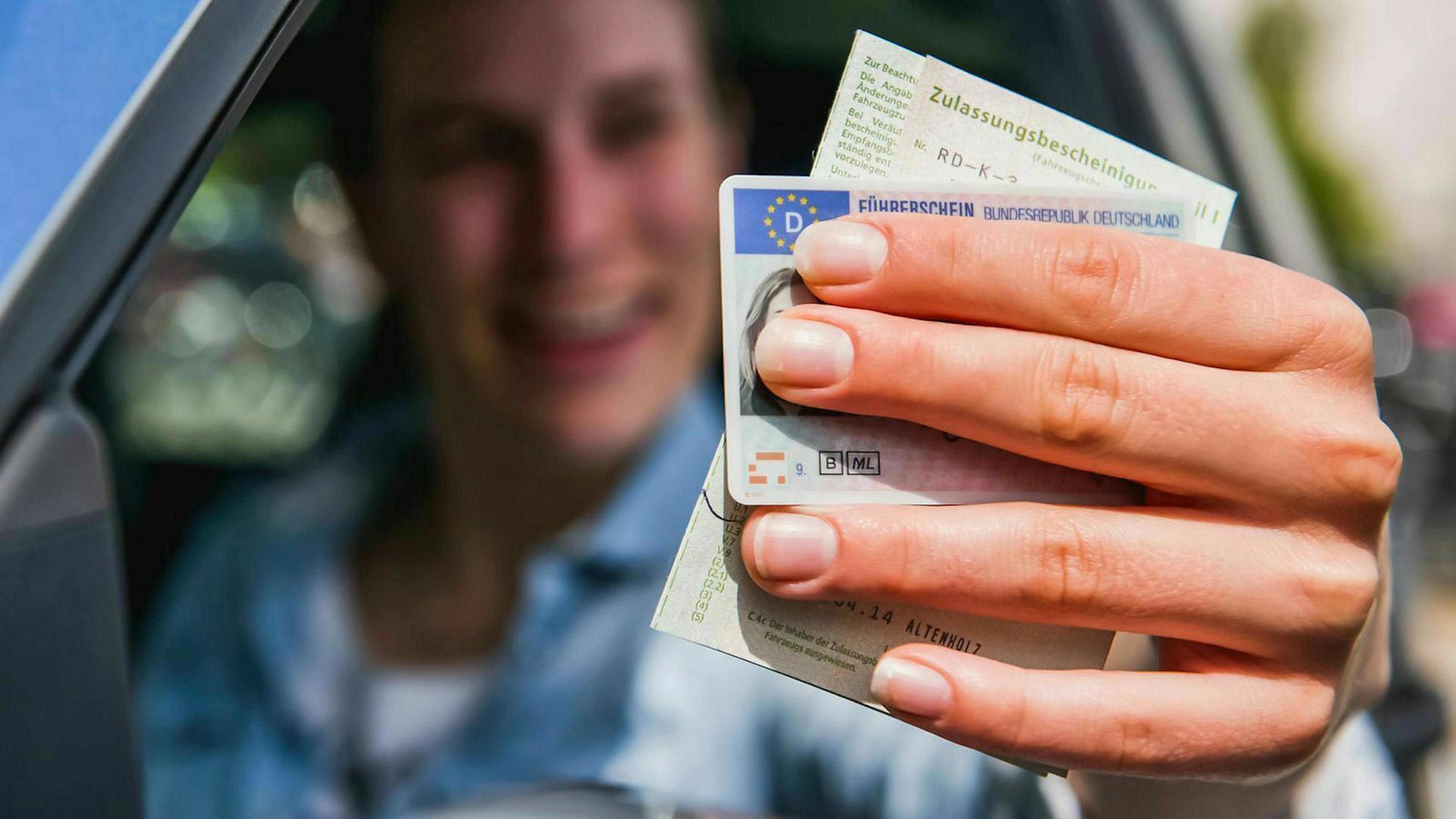 Ein Mann zeigt Führerschein und Fahrzeugpapiere aus dem Fahrerfenster.
