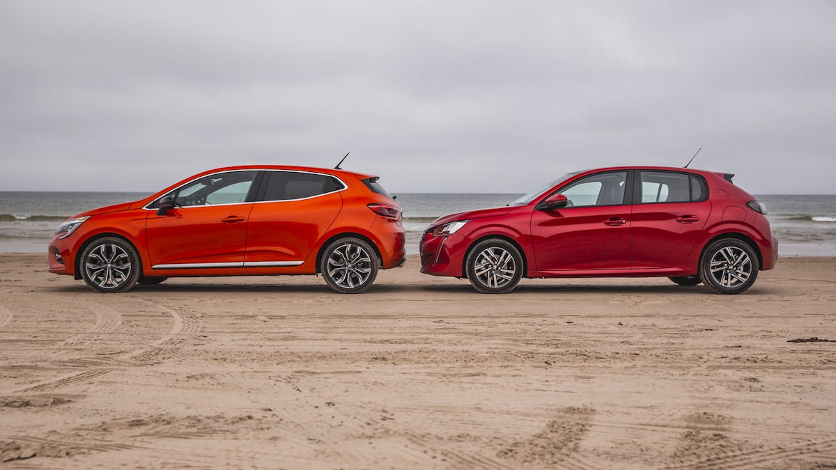 Peugeot 208 und Renault Clio in der Seitenansicht stehend am Strand. Das Meer im Hintergrund