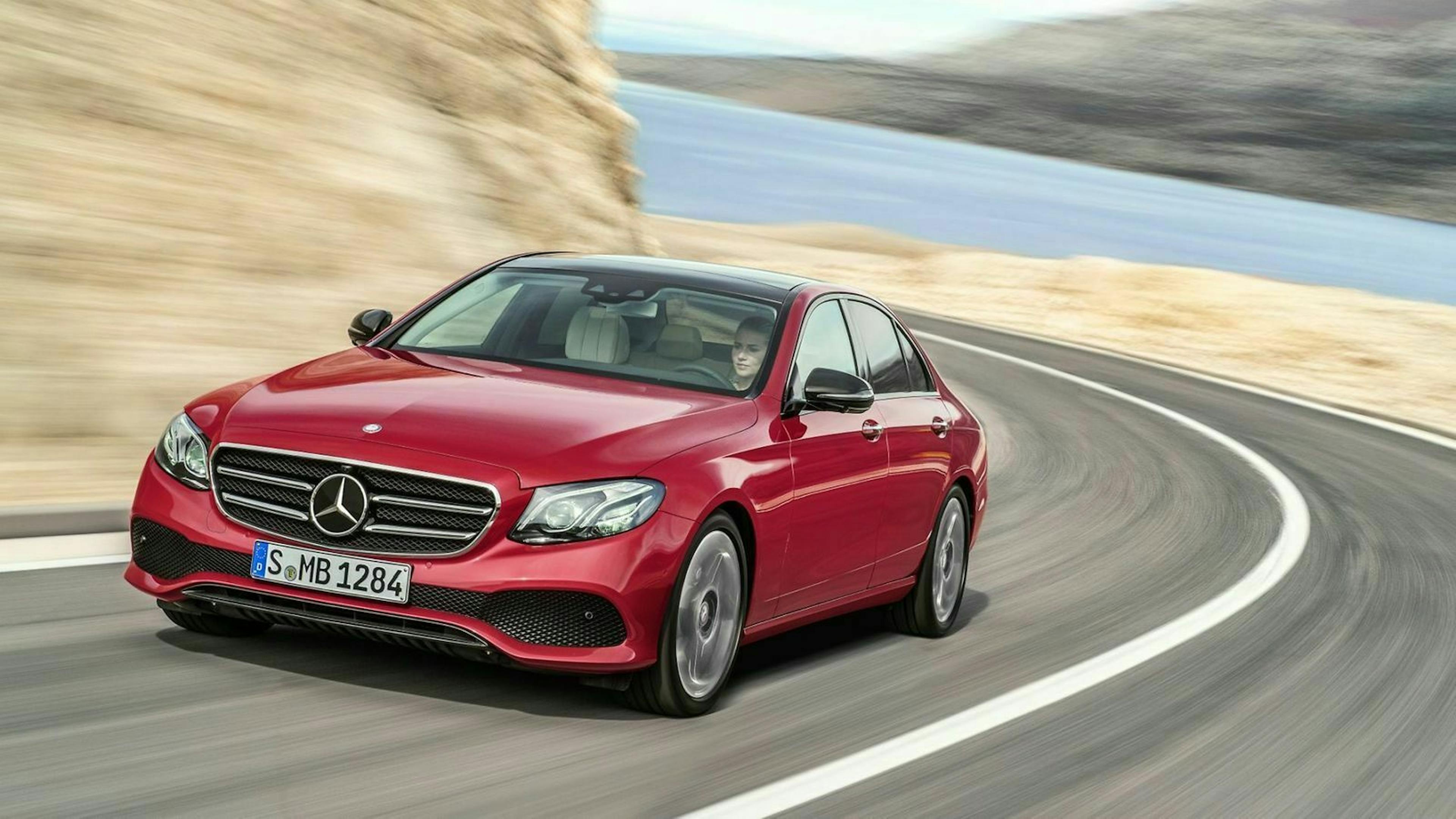 Zu sehen ist die Mercedes E-Klasse 220d. Er ist rot lackiert und rollt um eine Kurve
