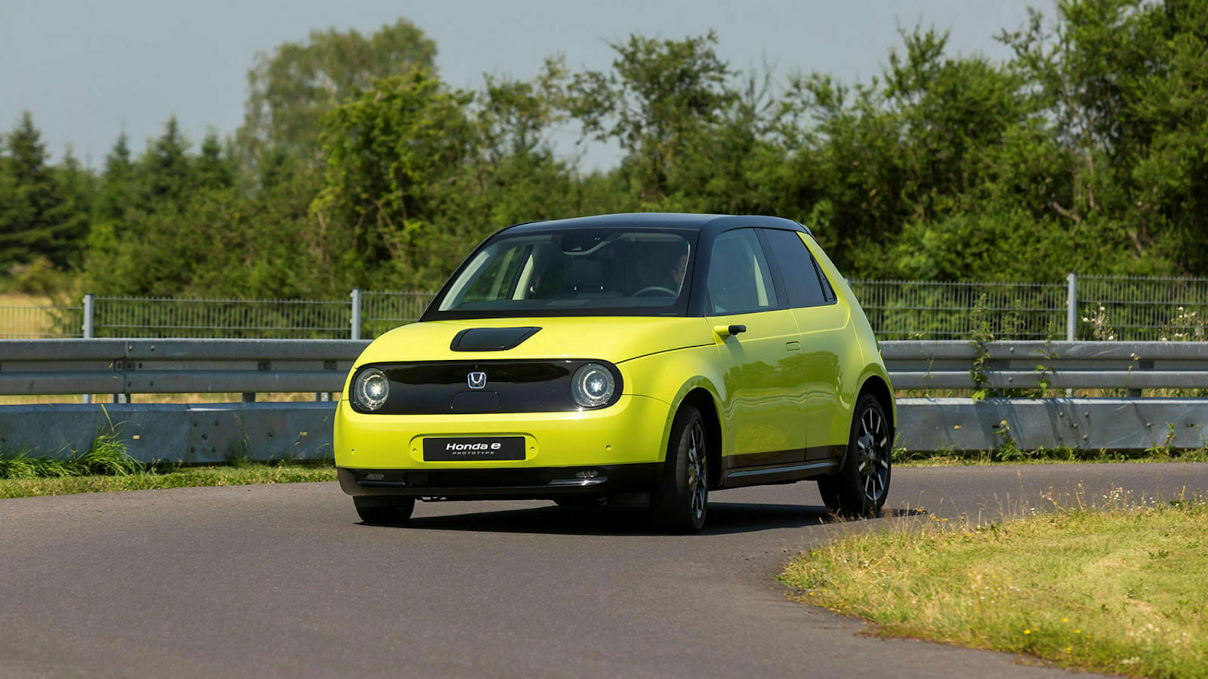 Ein grüner Honda E fährt eine Straße entlang.