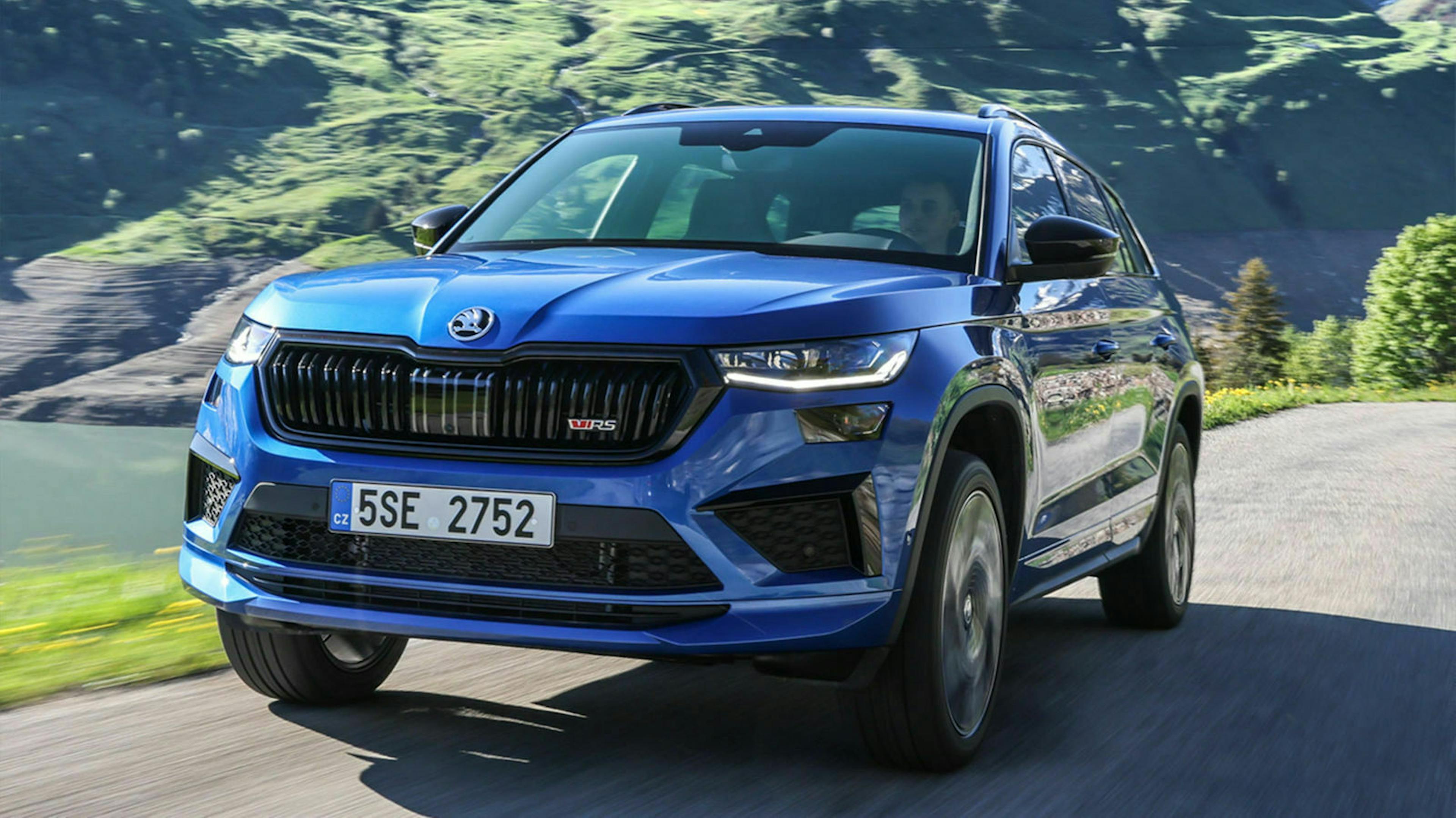 Ein blauer Skoda Kodiaq RS fährt über eine Landstraße