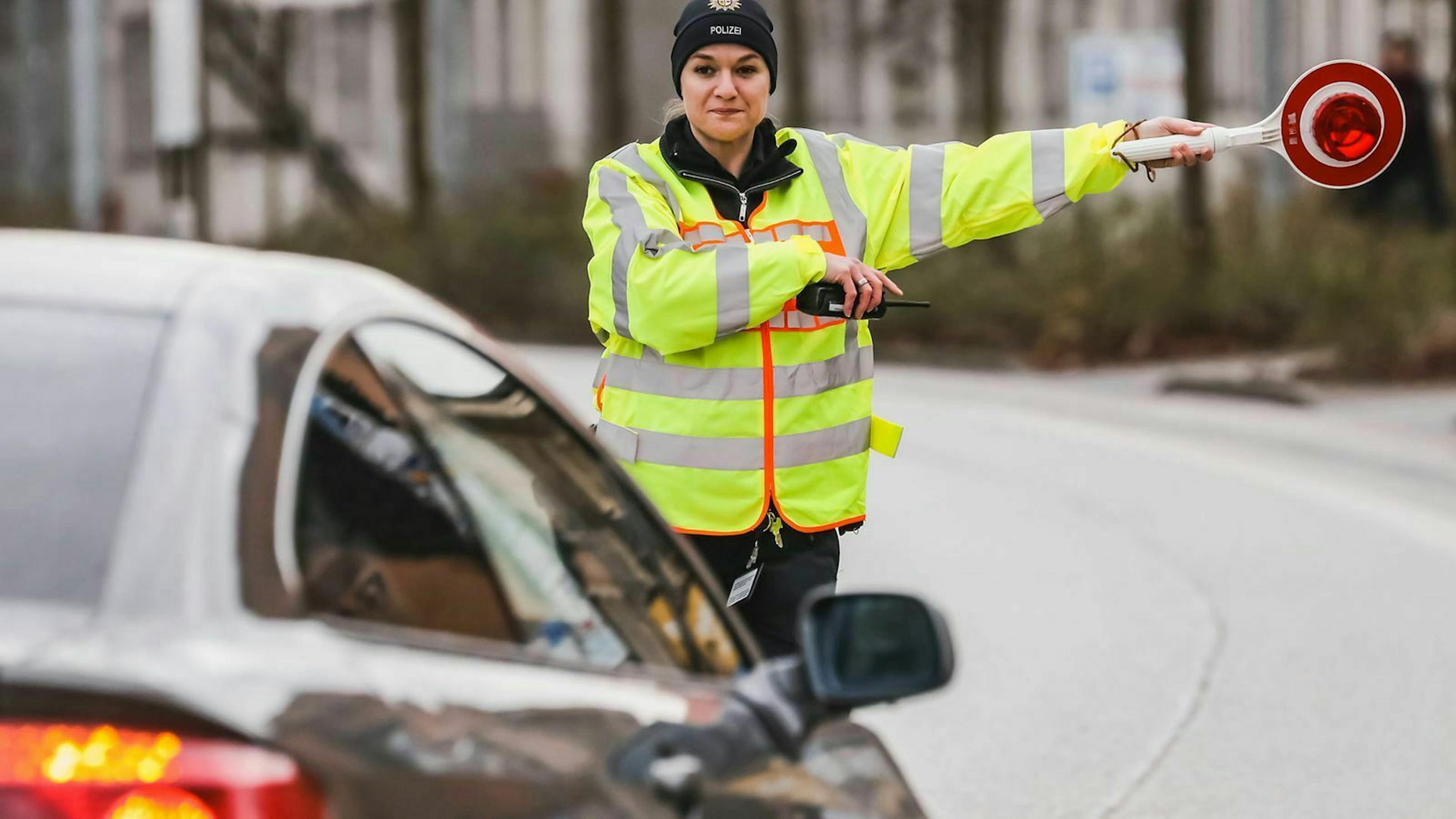 Bei einer Verkehrskontrolle winkt eine Polizistin ein Auto in eine Haltebucht.