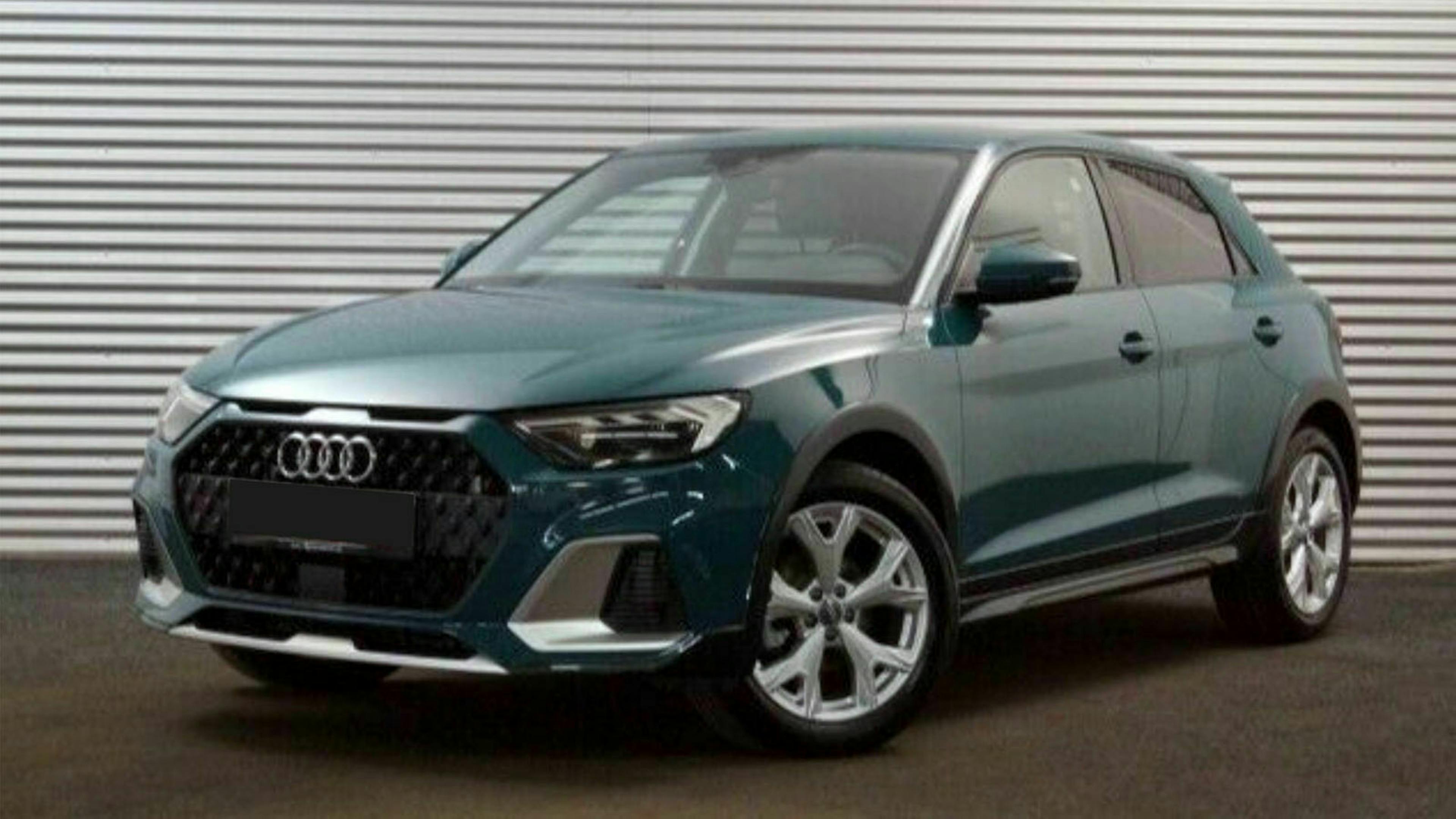Ein dunkelgrüner Audi A1 Citycarver steht vor einem grauen Rolltor