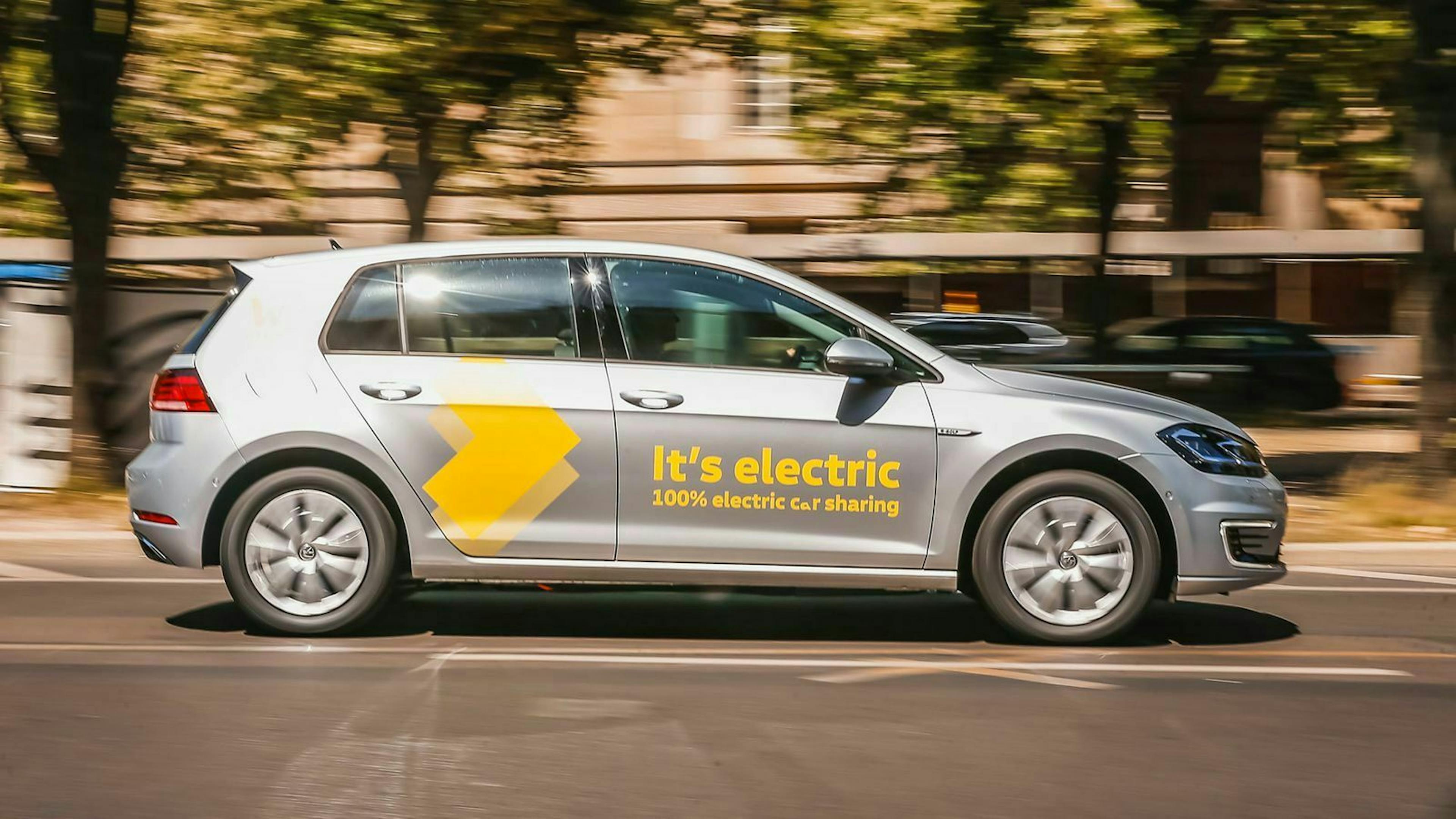Ein VW E-Golf fährt bei Sonnenschein eine Straße in Berlin entlang.