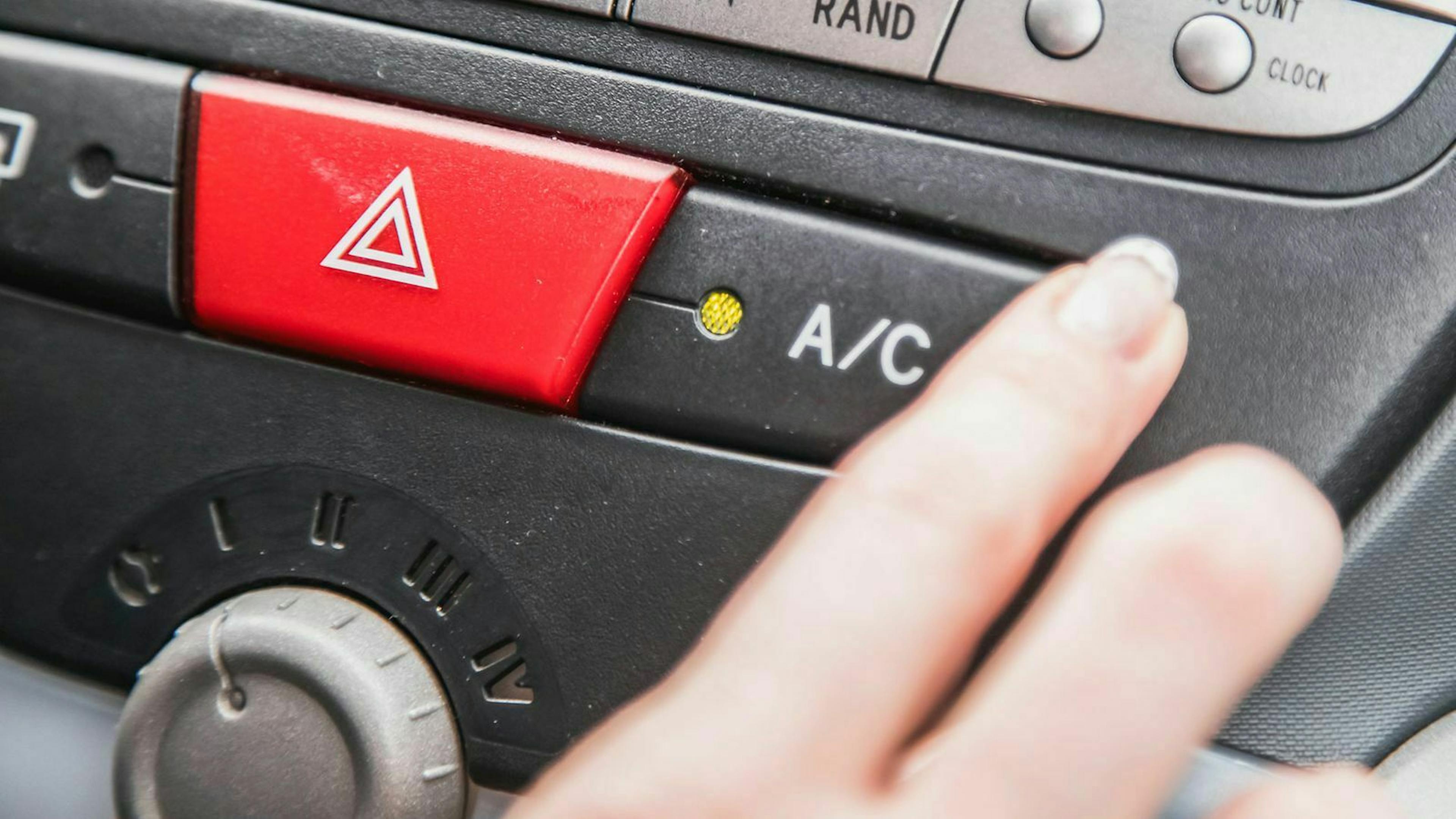 Jemand schaltet die Klimaanlage in seinem Auto ein. 