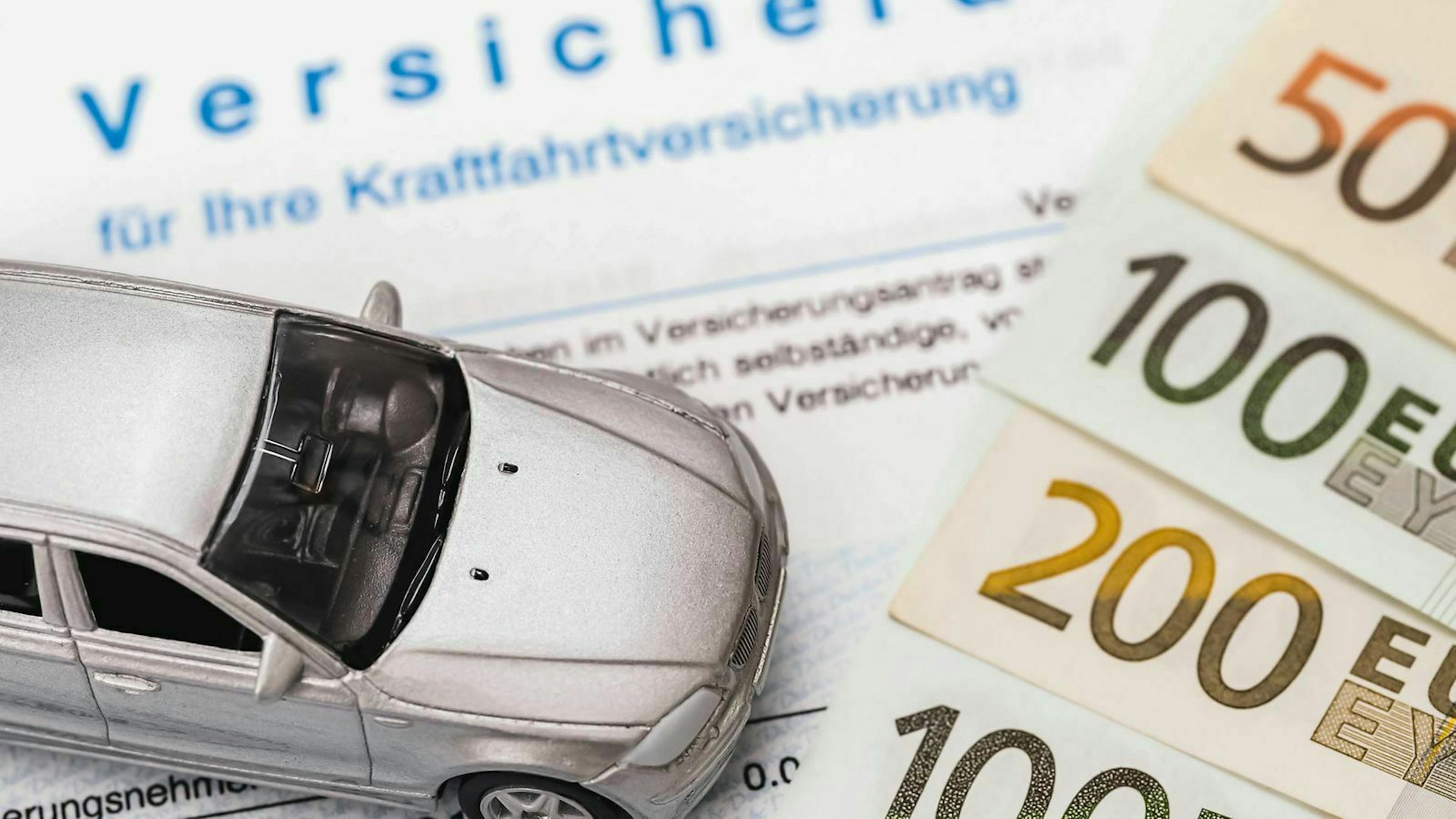 Ein Modellauto steht auf einem Mustervertrag einer Autoversicherung