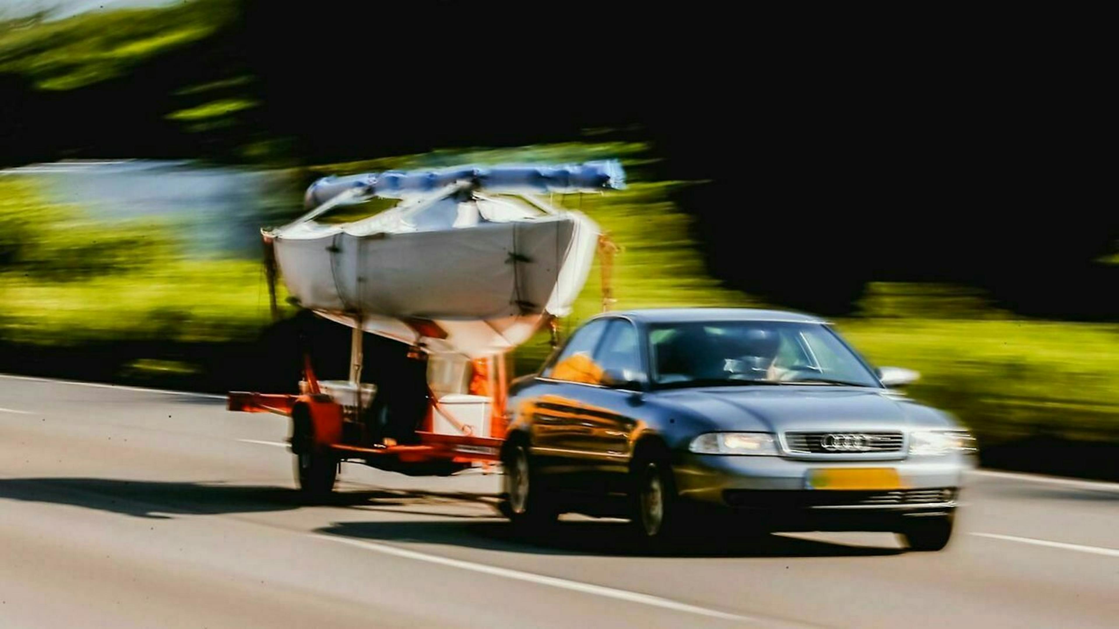 Eine Limousine  von Audi zieht einen Anhänger mit einem Boot darauf.