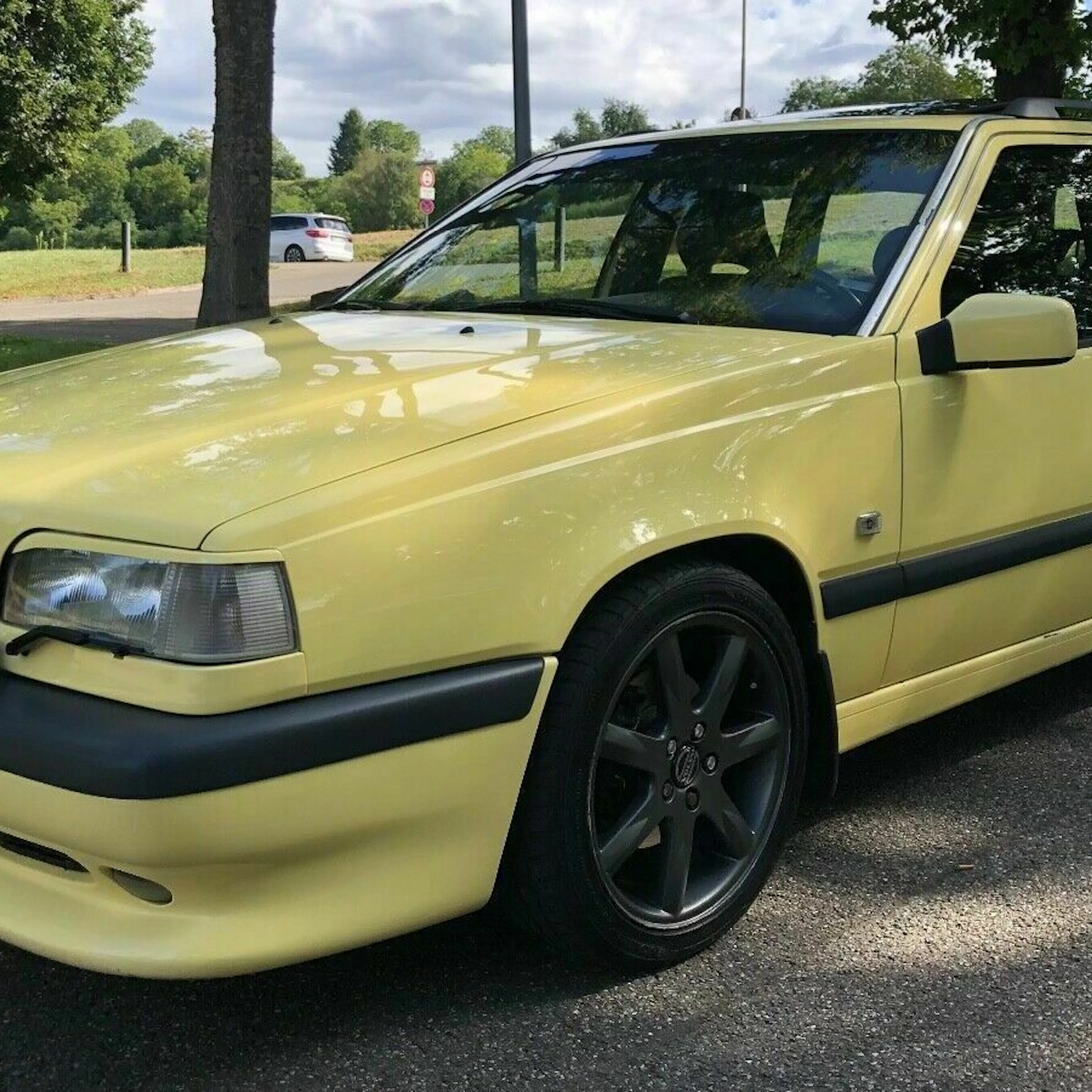 Ein gelber Volvo 850 Oldtimer parkt am Rand einer Straße.