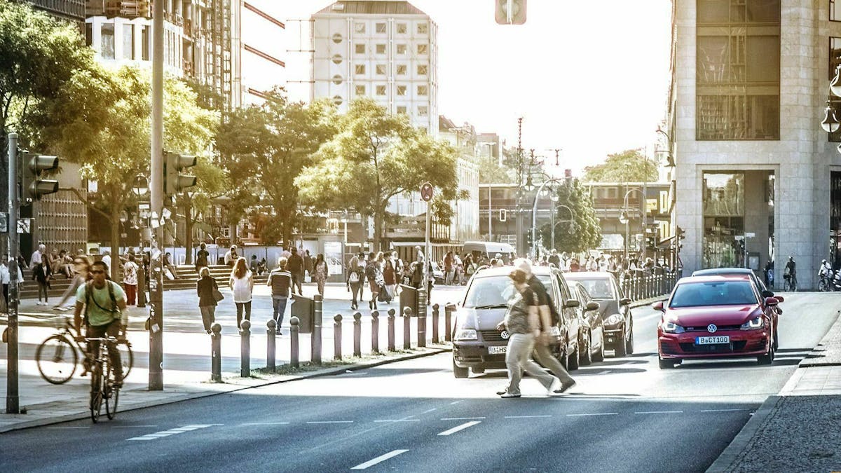 Eine Szene aus dem Straßenverkehr in Berlin: Fußgänger und Radfahrer queren eine Ampel während Autos warten