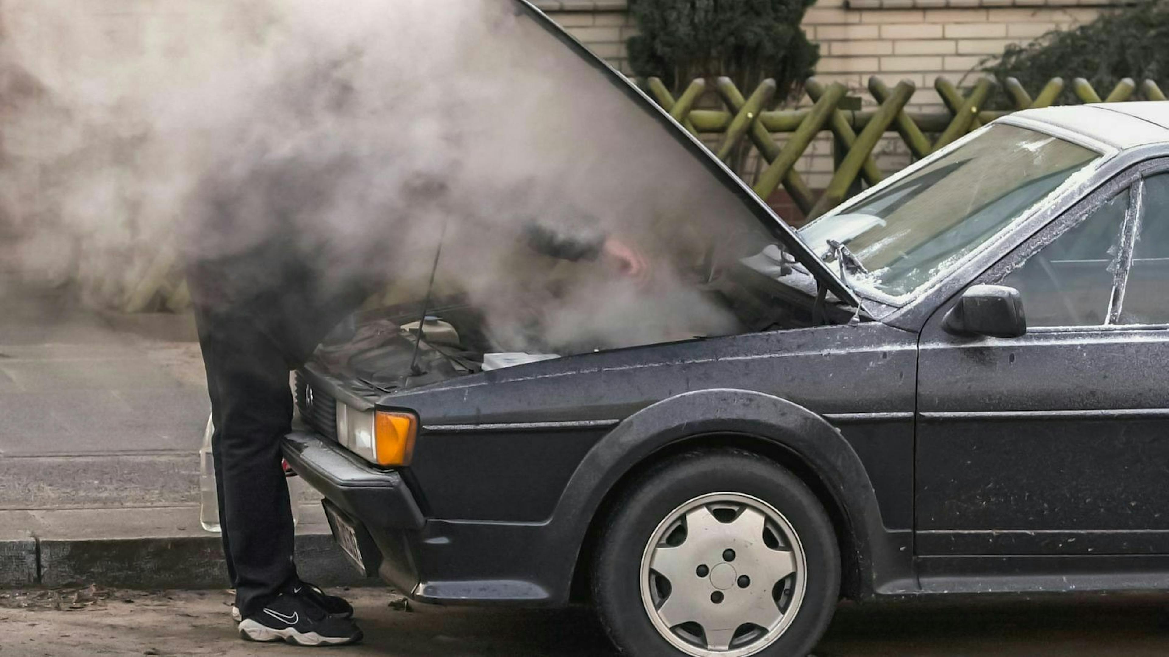 Ein mann taut den Kühler seines Autos auf. 
