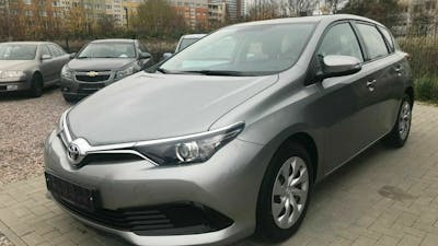 Ein silberner Toyota Auris steht auf einem Parkplatz vor einem Hochhaus