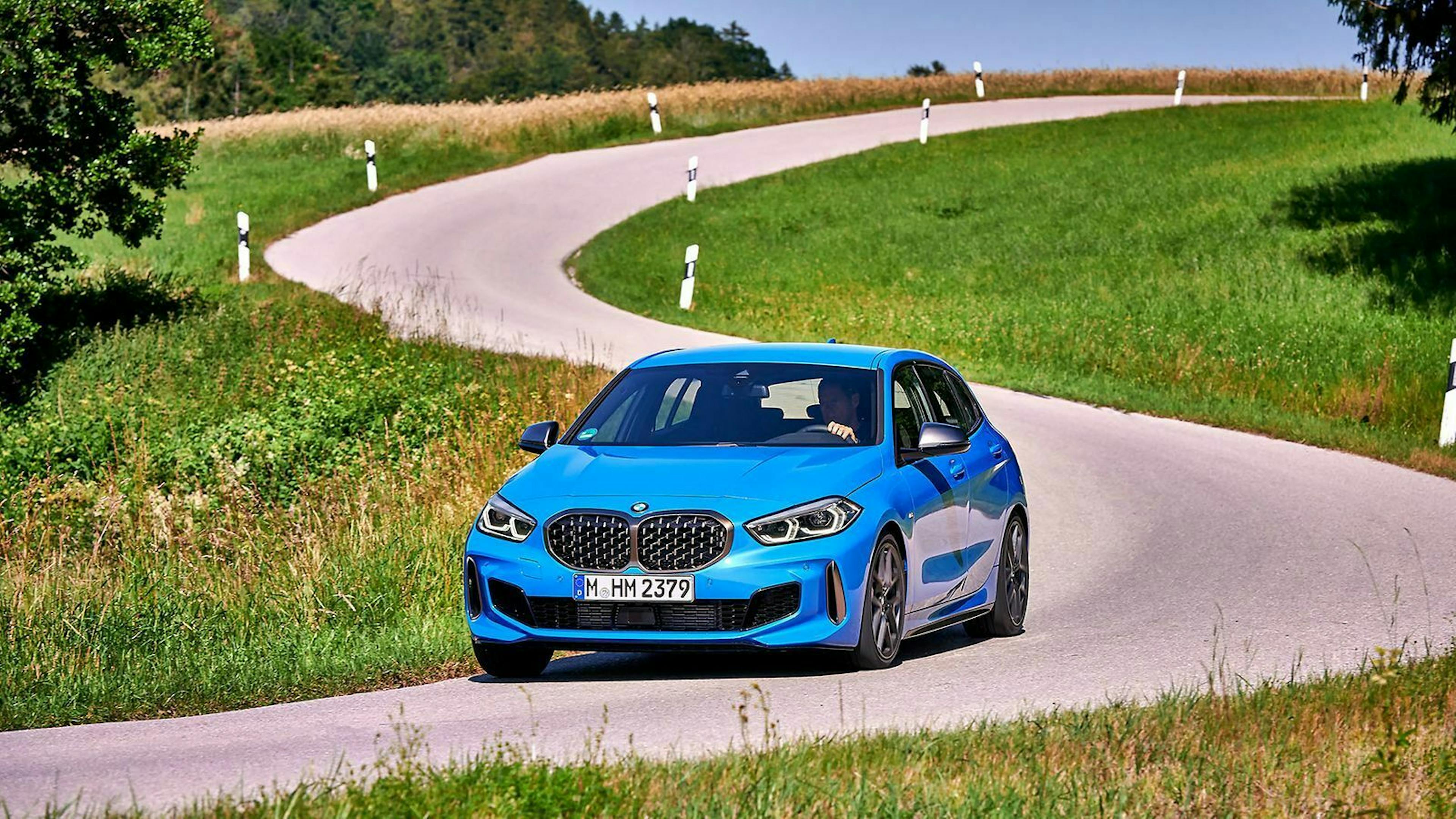 Ein blauer BMW M135i xDrive in der Kurve - Frontansicht