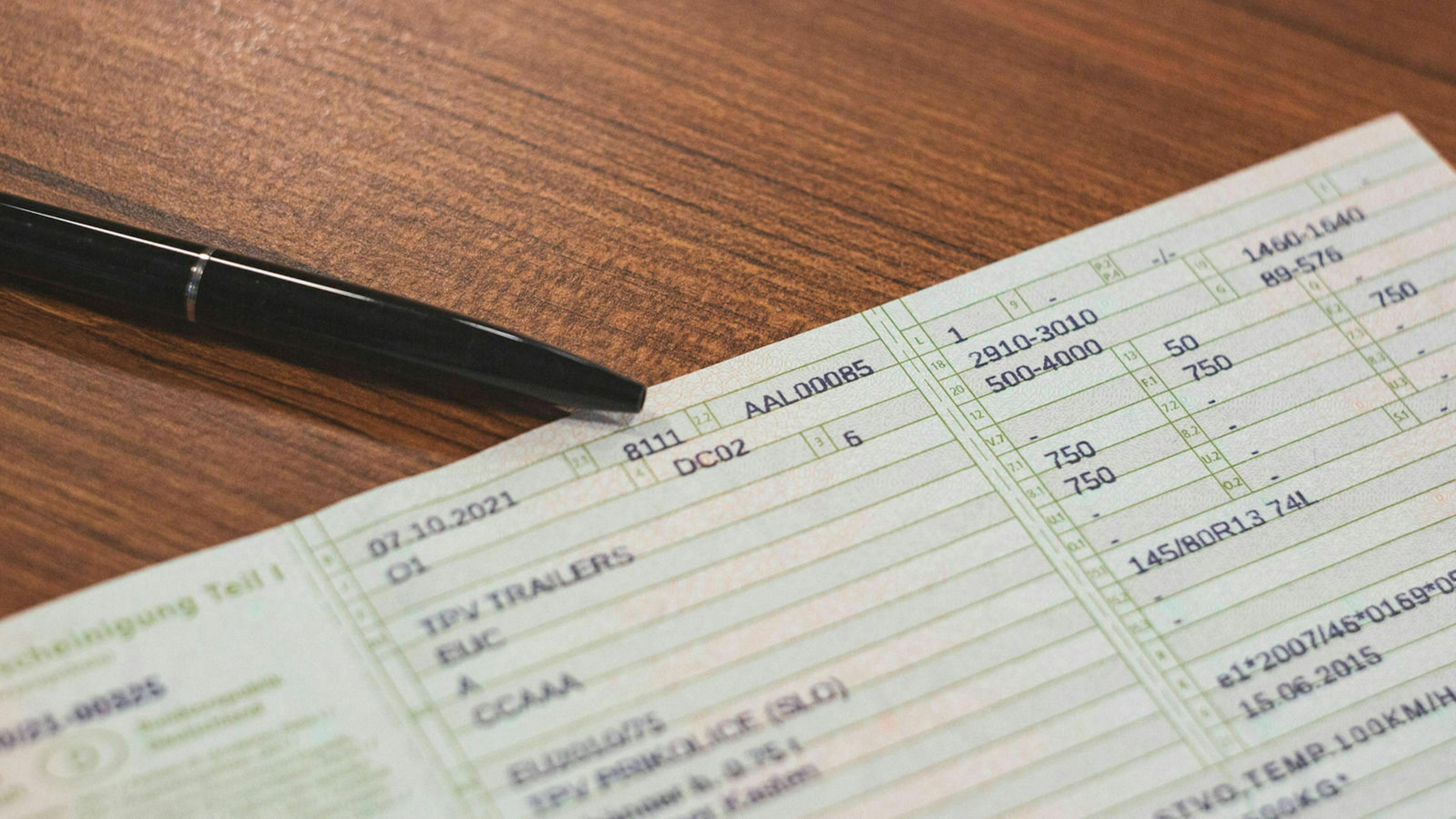 Ein Fahrzeugschein mit Kuli auf einem Schreibtisch