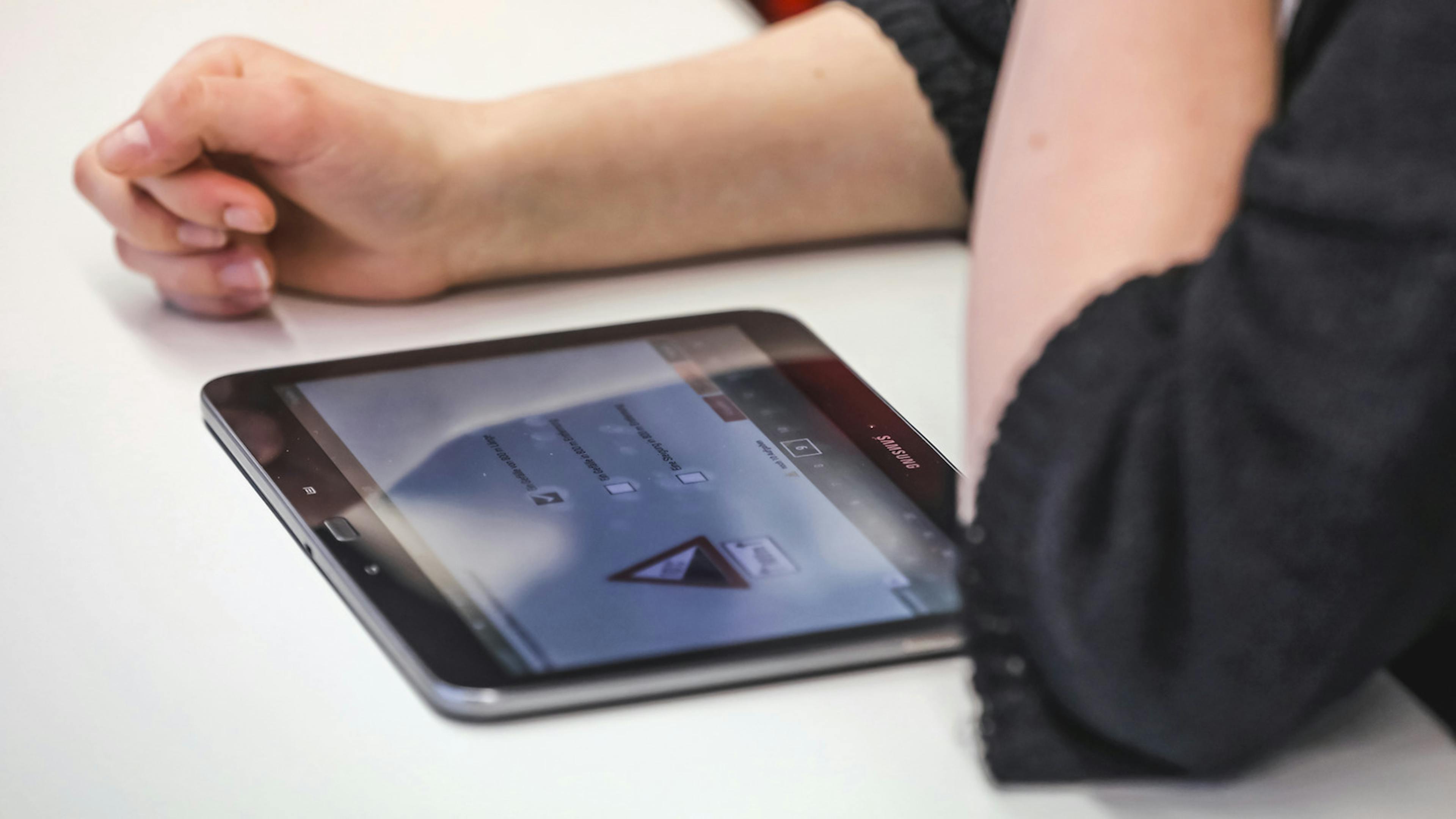 Jemand sitzt vor einem Tablet, auf dem eine Führerschein-App zu sehen ist