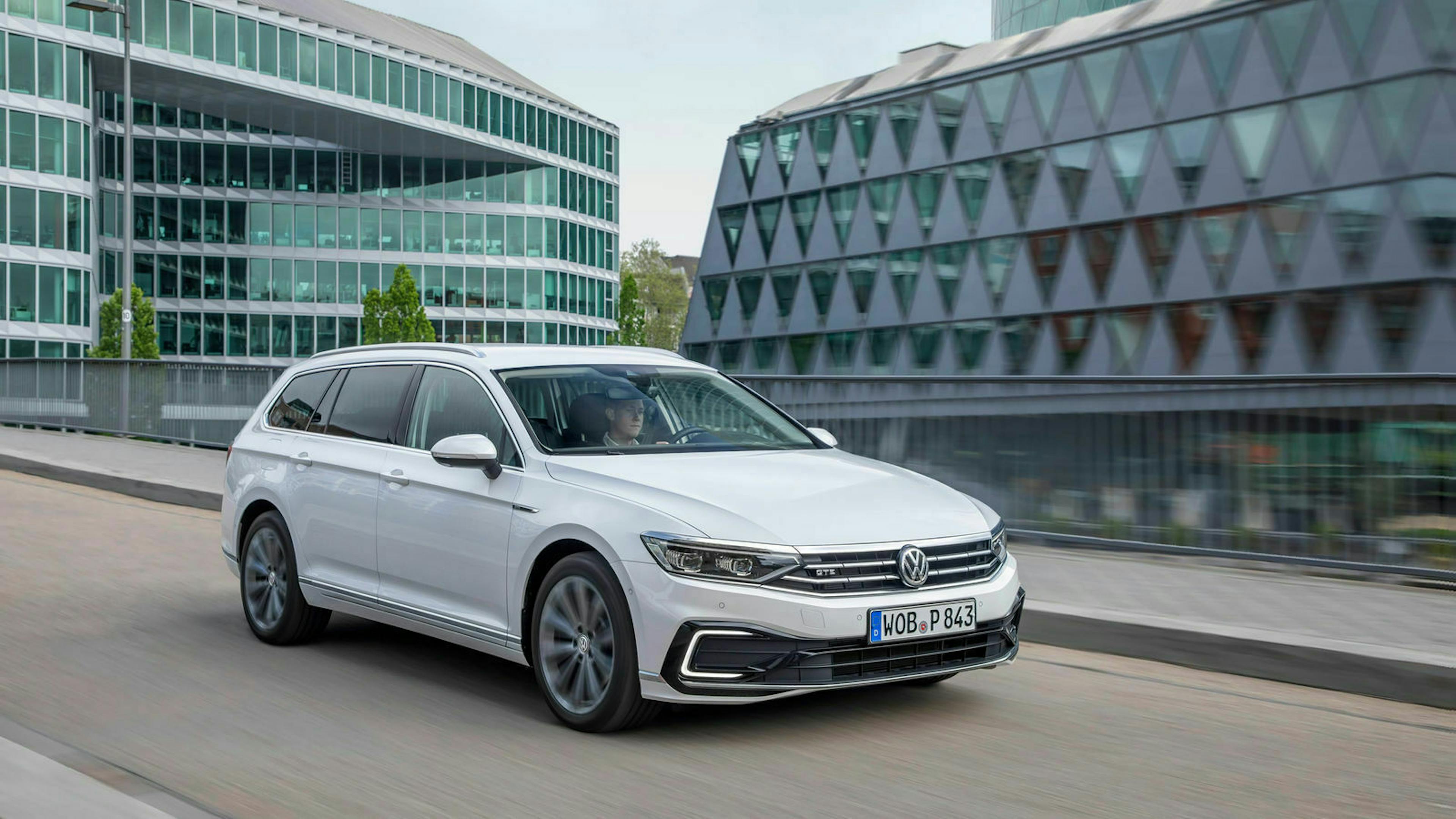 Ein weißer VW Passat fährt über eine Brücke in einer Stadt