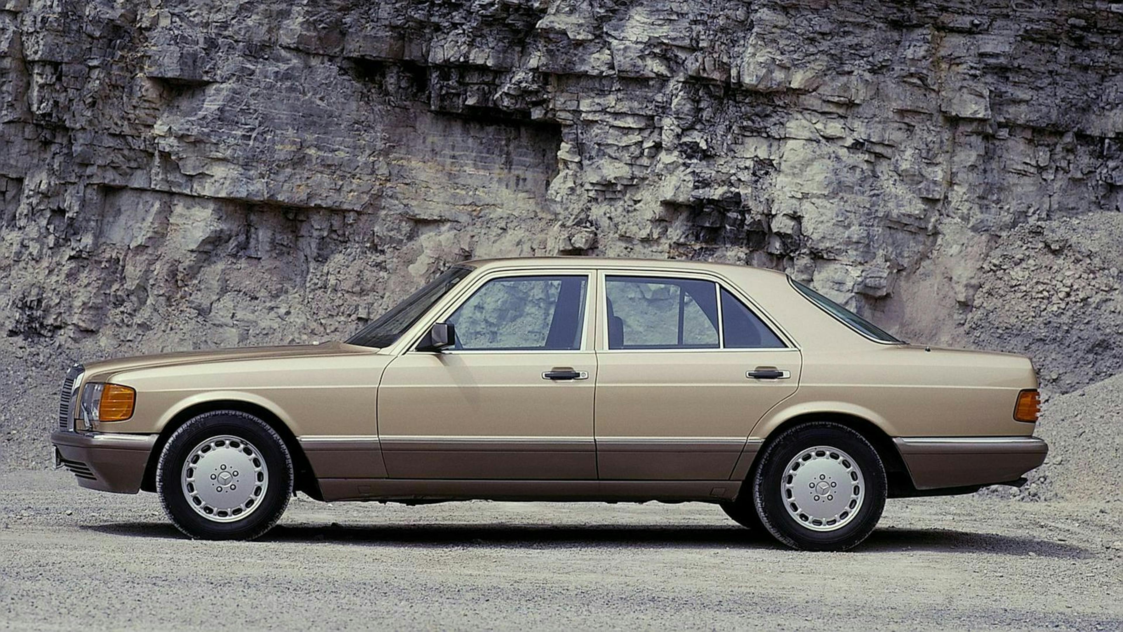 Klassisches hellbraunes Auto vor einer Felswand, seitlich aufgenommen, elegante Limousine mit klaren Linien und silbernen Felgen.