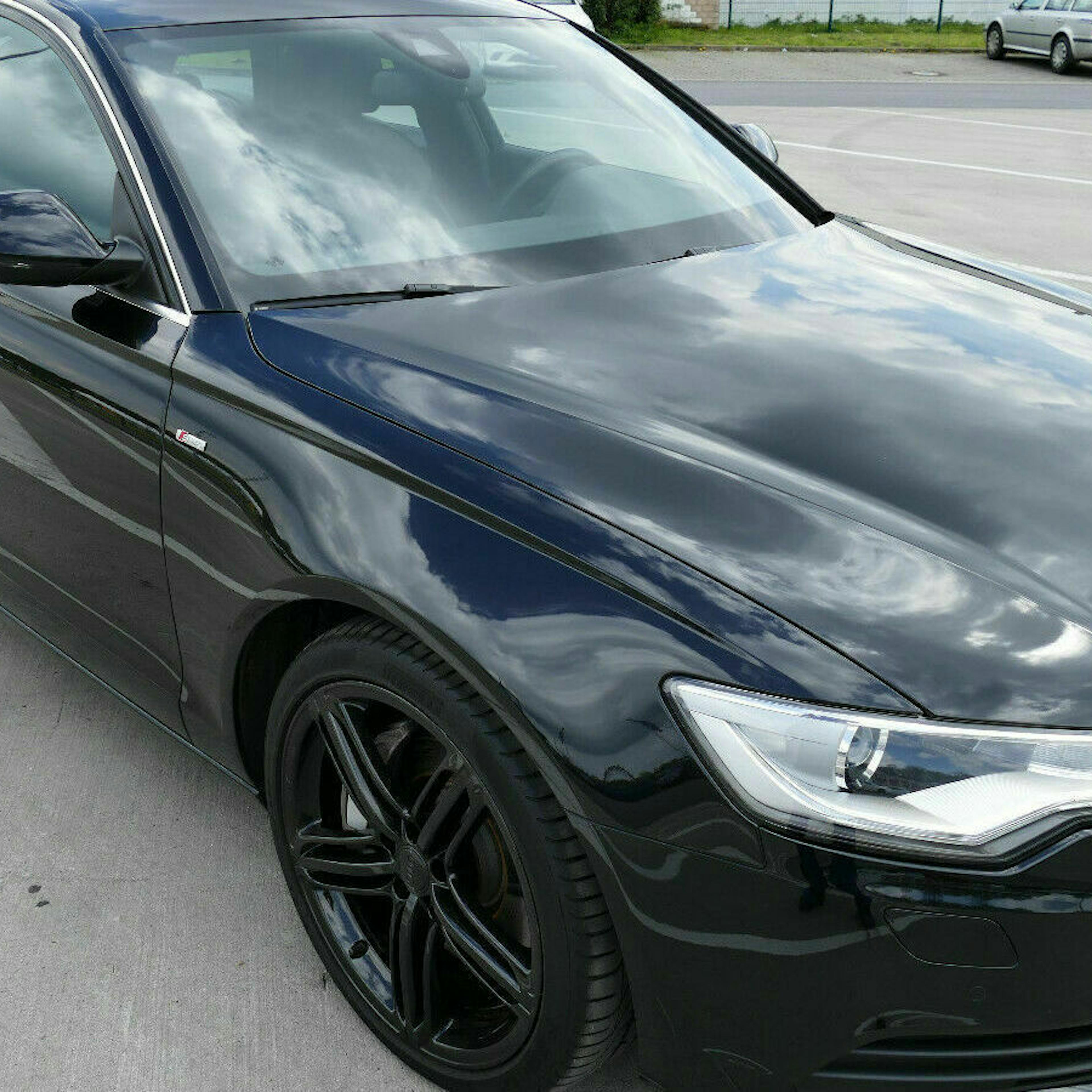 Ein schwarzer Audi A6 mit Panoramadach steht auf einem Parkplatz.