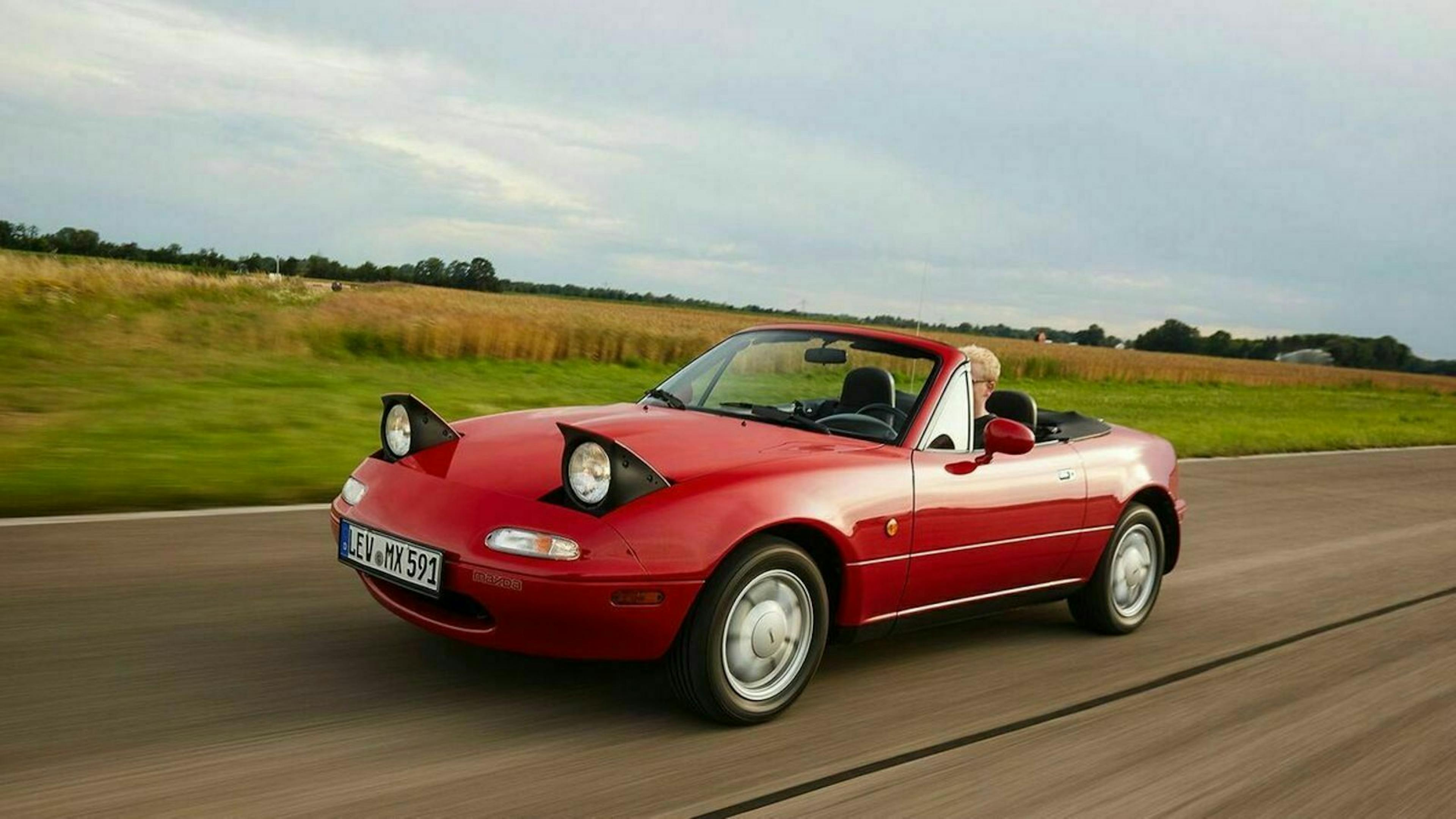 Ein rotes Madza MX-4 NA Cabrio fährt eine Landstraße entlang