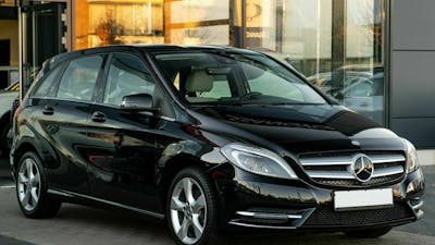 Eine schwarze B-Klasse von Mercedes-Benz steht vor einem Gebäude mit bodentiefen Fenstern