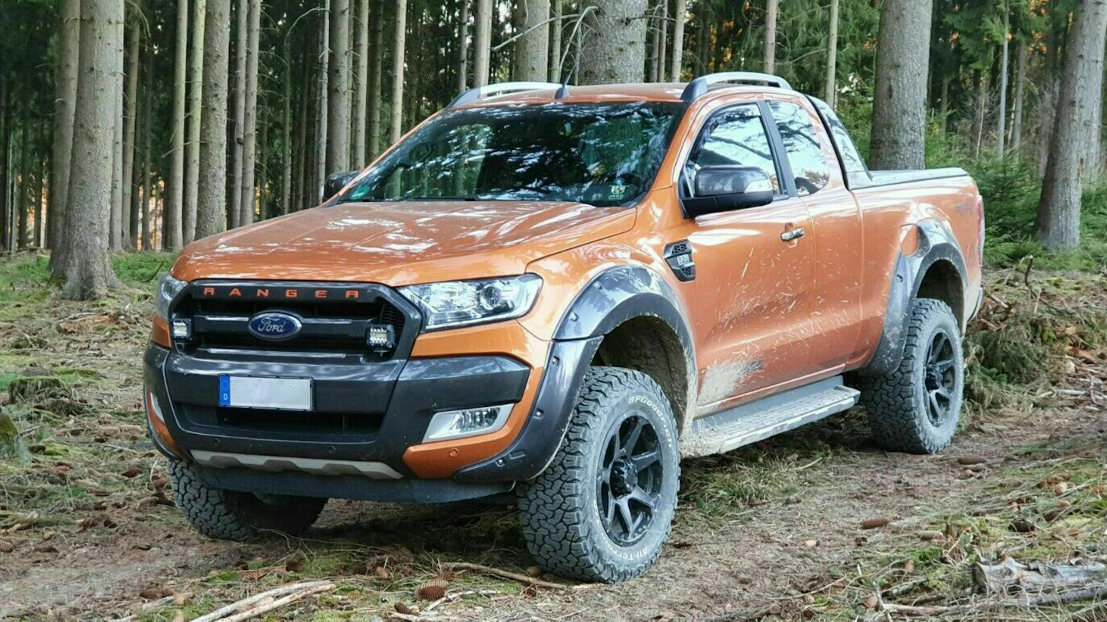 Ein orangefarbener Ford Ranger Pick-up steht an einem Waldrand.