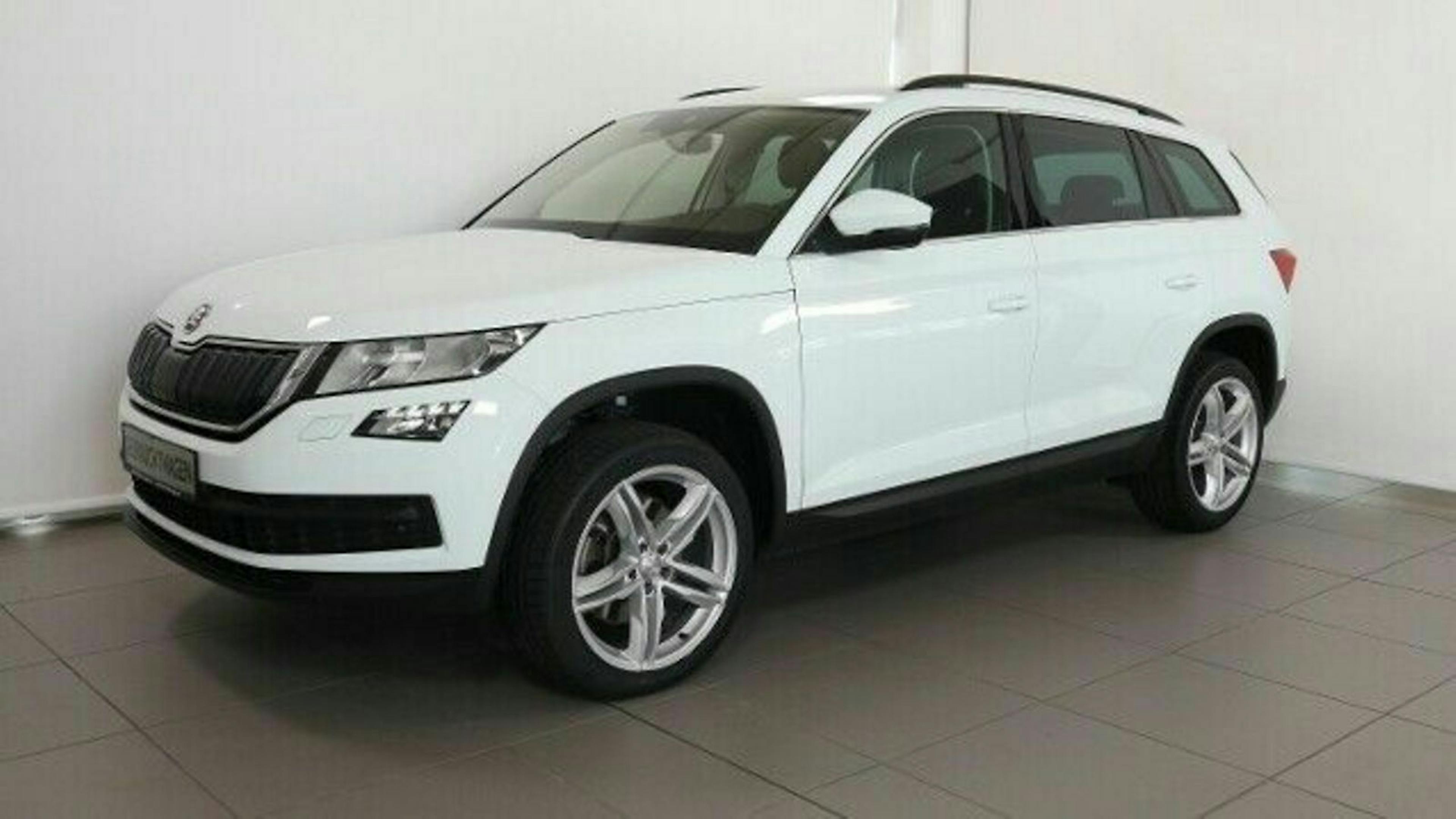 Weißer SUV, seitlich fotografiert, auf grauem Boden in einem hellen Raum. Der Wagen hat fünf Türen und silberne Felgen.