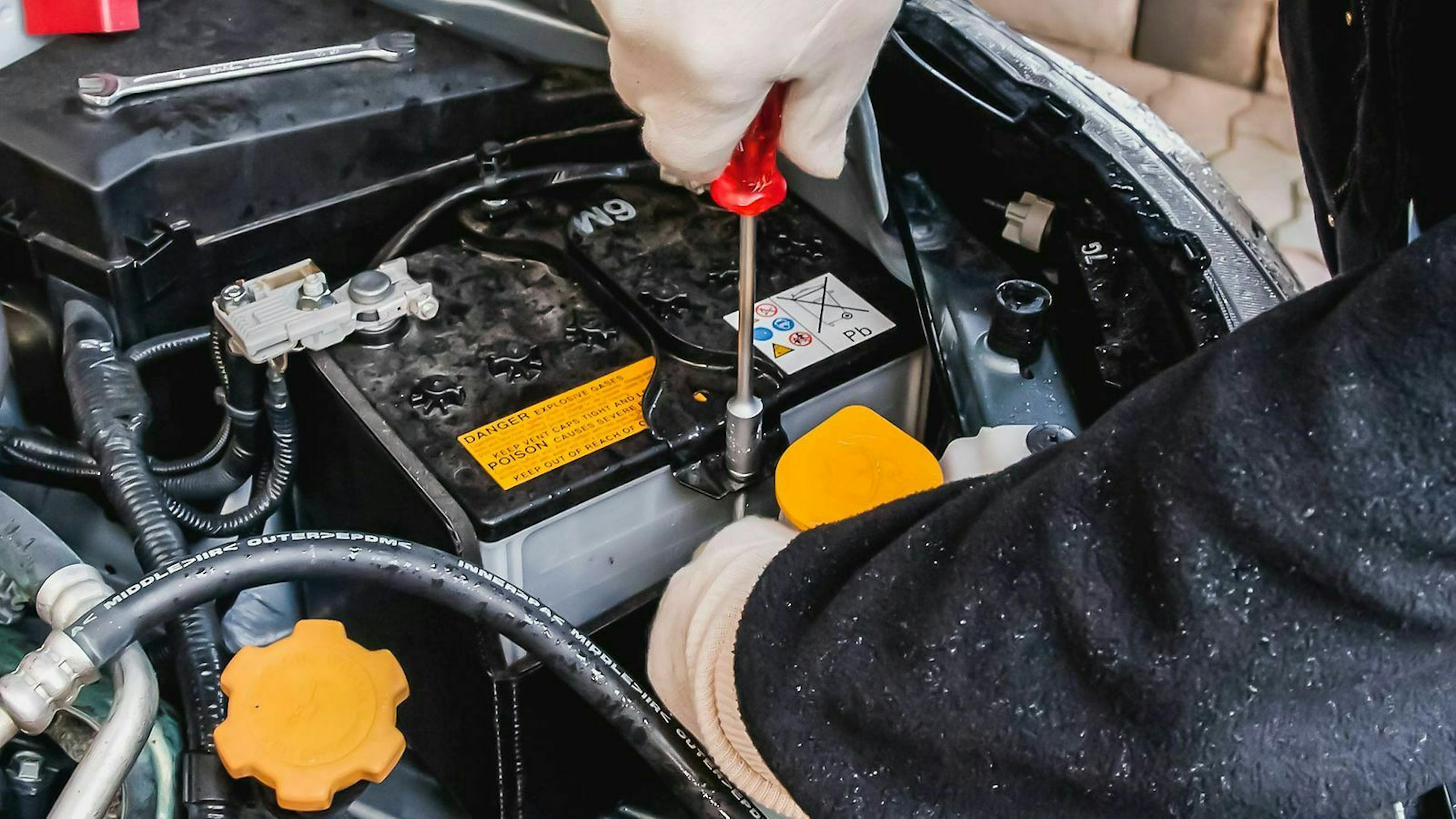 Jemand baut die Batterie seines Autos aus.