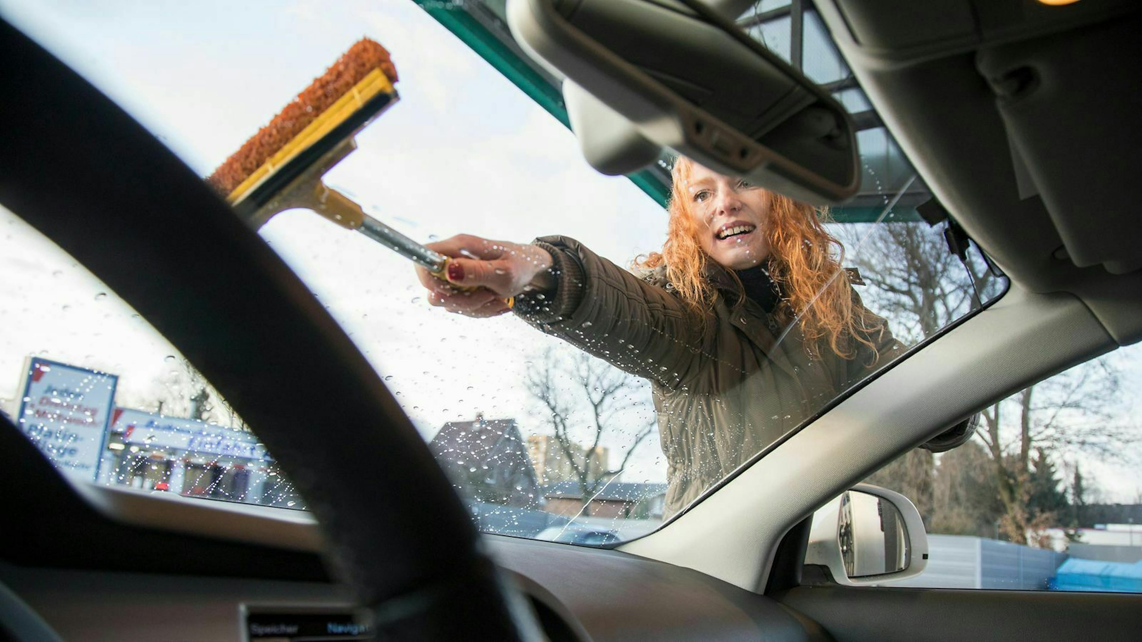 frau-putzt-windschutzscheibe-ihres-autos-95632494_1