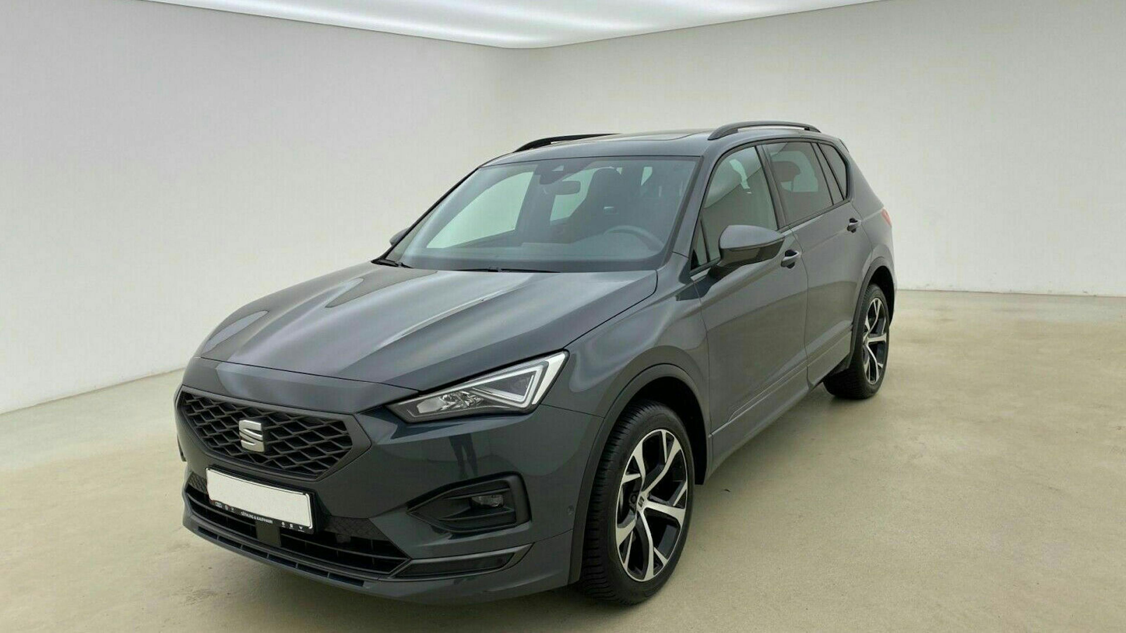 Ein schwarzer Seat Tarraco steht in einem Raum vor einer weißen Wand