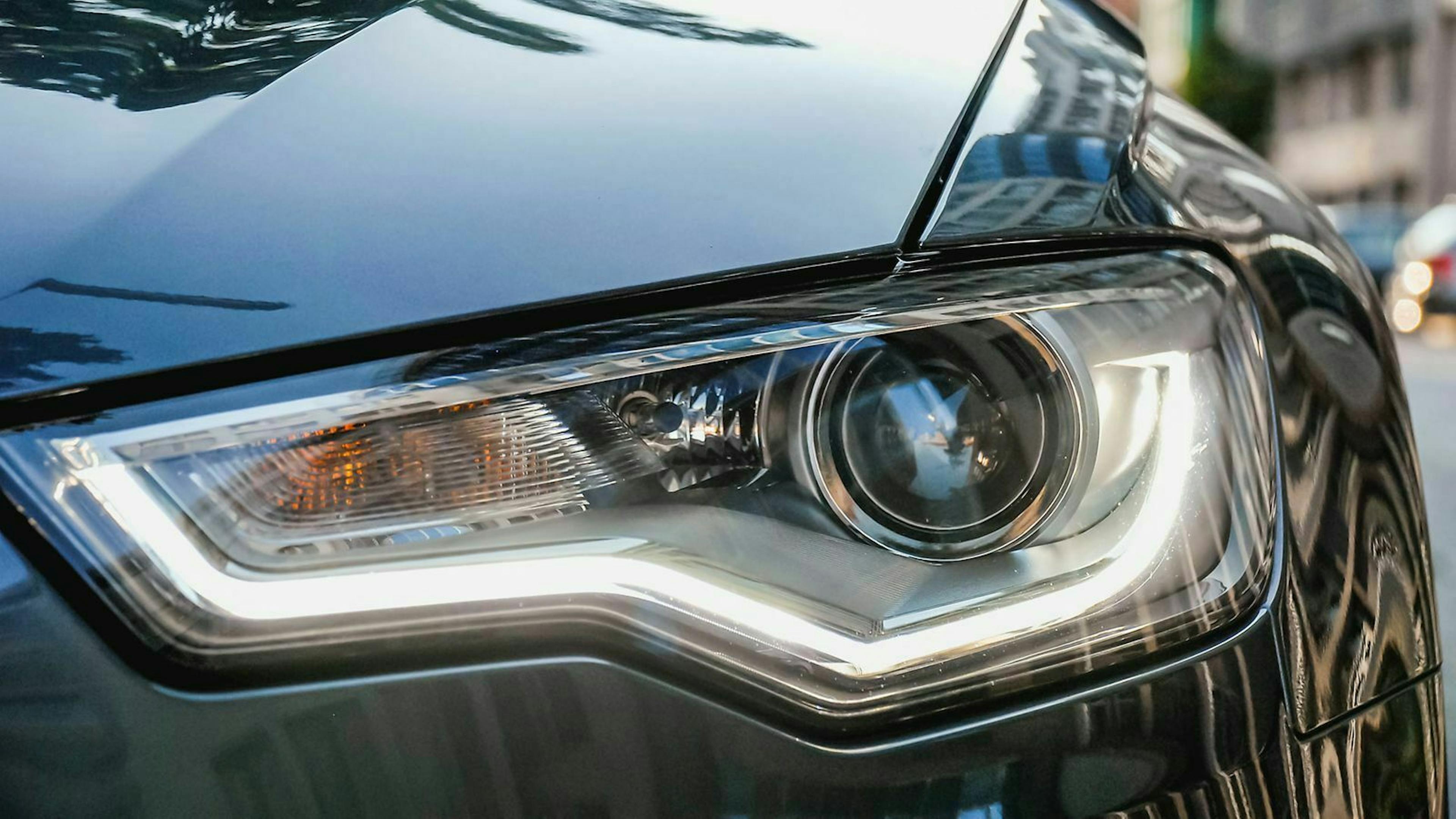 Im Scheinwerfer eines grauen Audi A6 leuchtet das Tagfahrlicht.