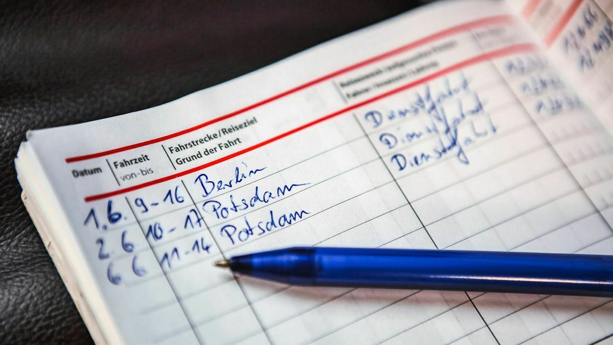 Ein blauer Stift liegt auf einem Fahrtenbuch für den Dienstwagen. Es sind Fahrten nach Berlin und Potsdam eingetragen.