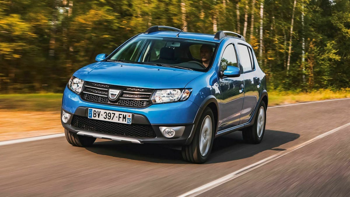 Ein blauer Dacia Sandero Stepway fährt über eine Landstraße.