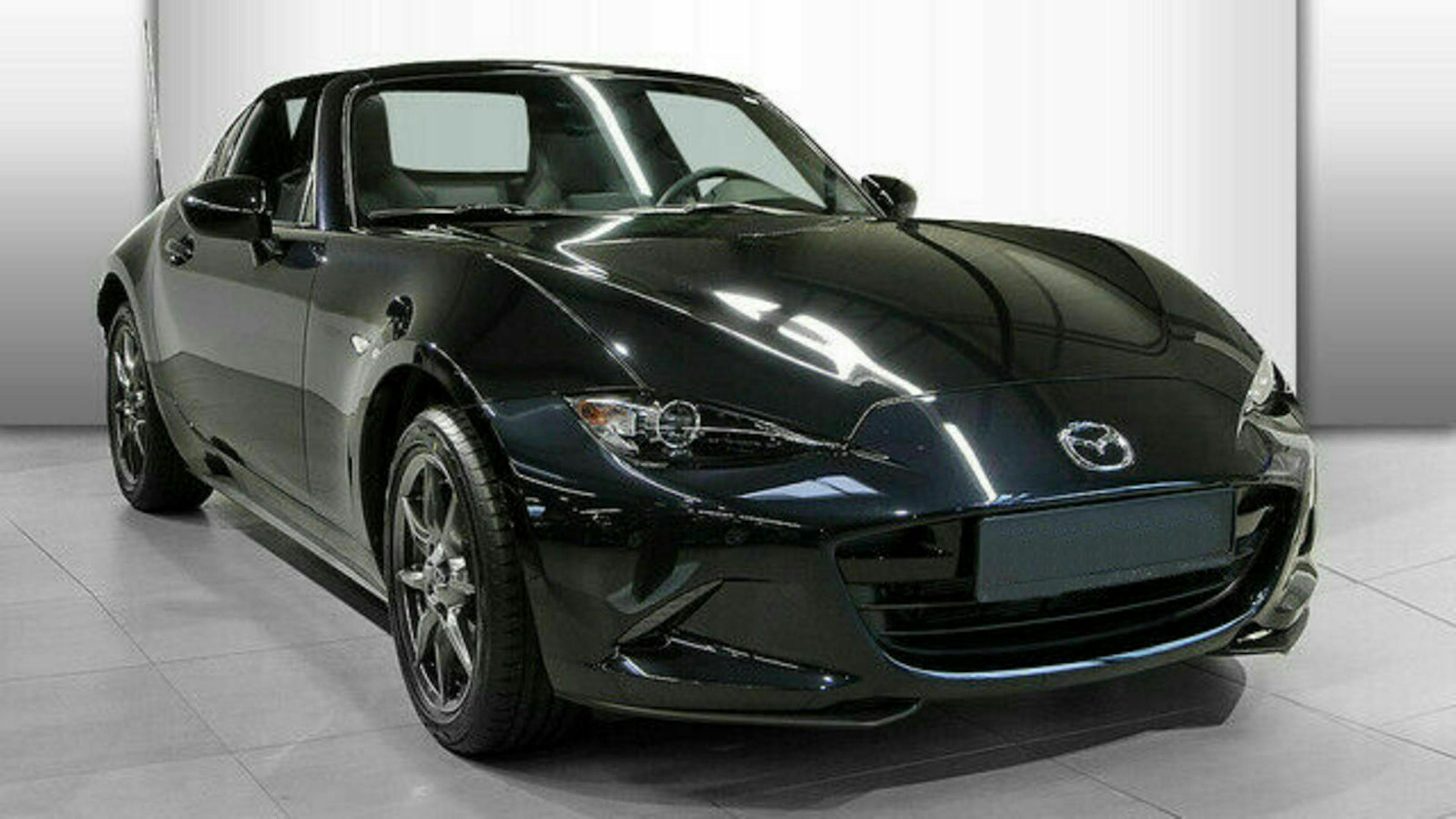 Ein schwarzer Mazda MX-5 mit Heckantrieb steht in einem hellen Raum
