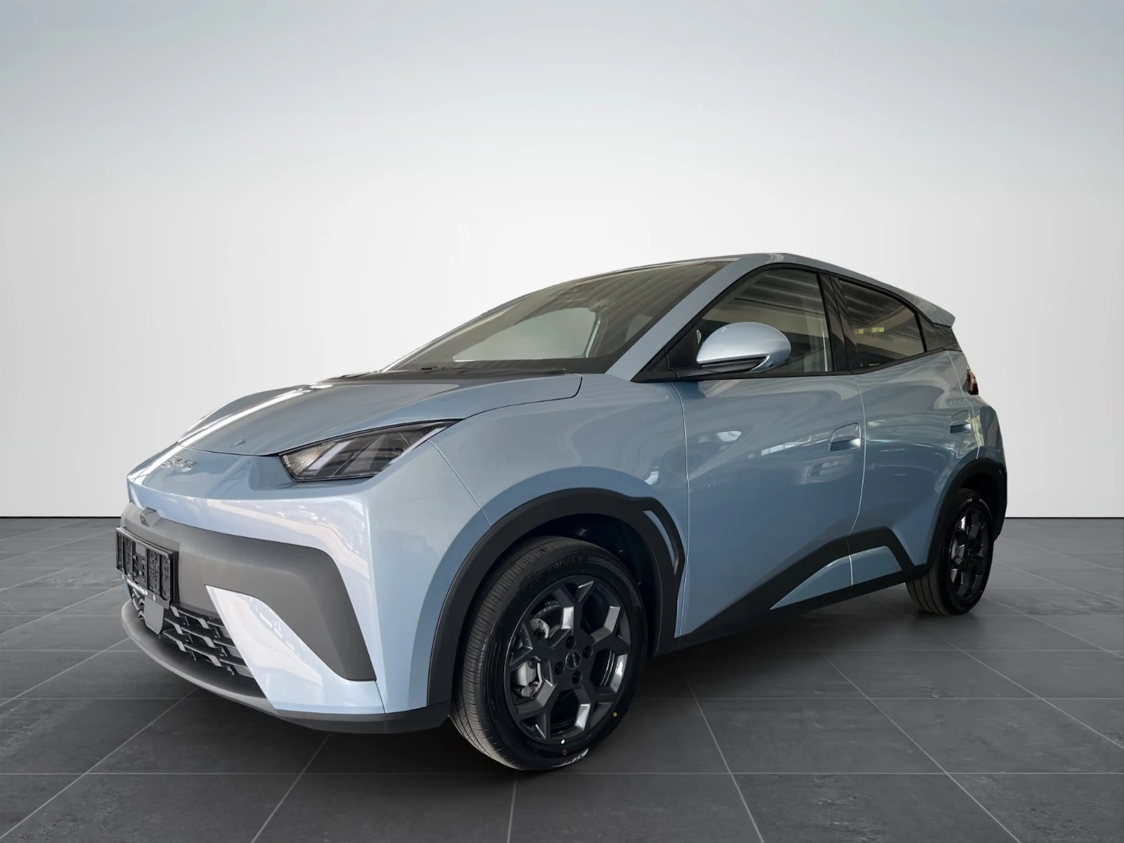 Ein graublauer BYD Dolphin Surf steht auf einer Präsentationsfläche.