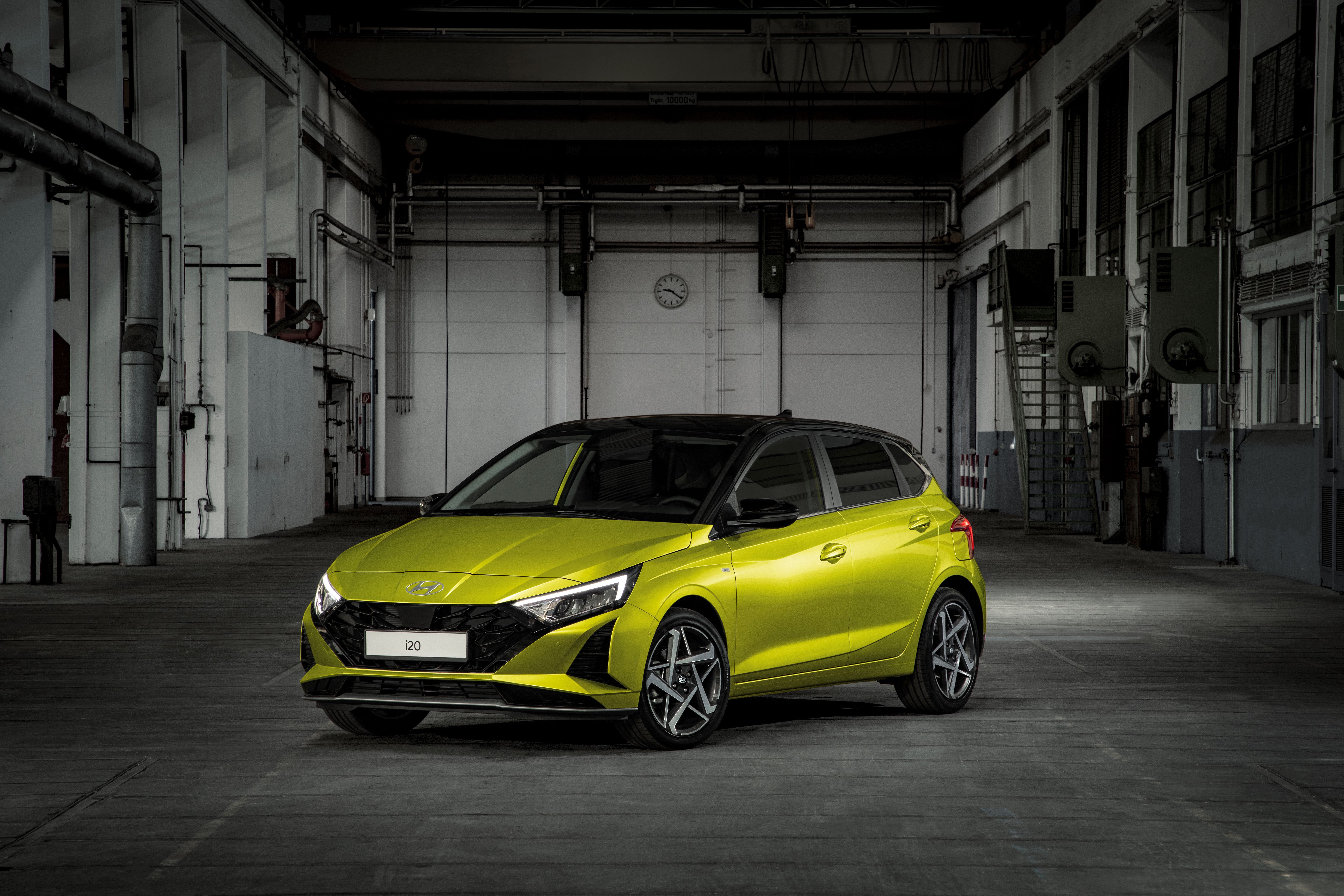Limettengelber Hyundai i20 mit schwarzem Dach und schmalen LED-Scheinwerfern in einer dunklen Fabrikhalle.