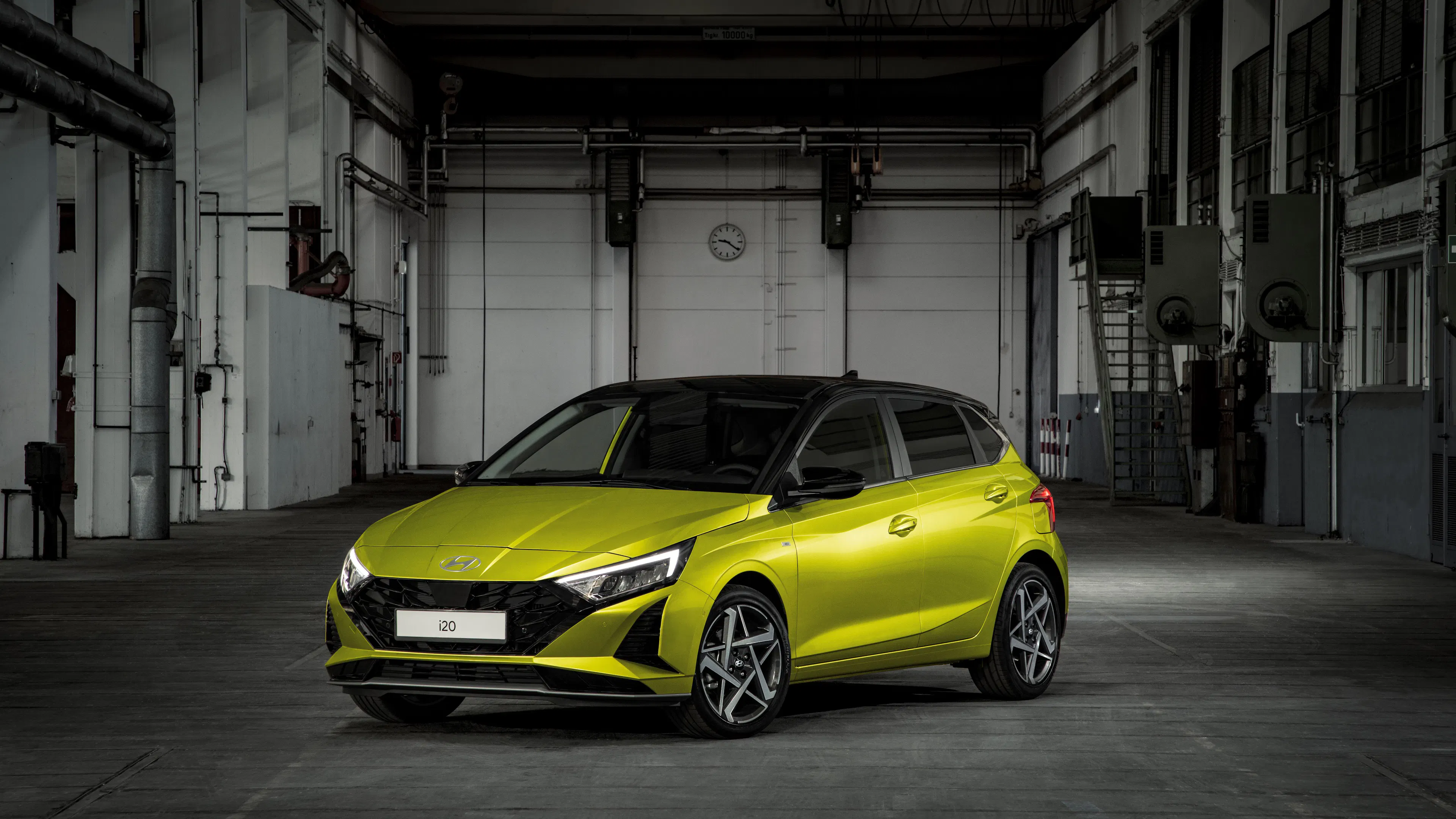 Limettengelber Hyundai i20 mit schwarzem Dach und schmalen LED-Scheinwerfern in einer dunklen Fabrikhalle.
