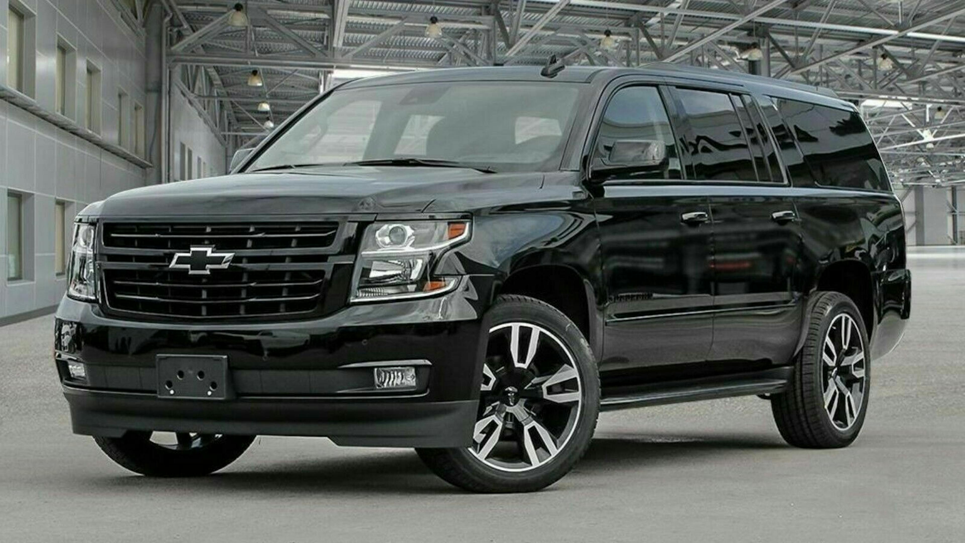Schwarzer SUV der Marke Chevrolet in einer modernen Halle, frontal seitlich aufgenommen, mit markanten Felgen und glänzendem Lack.