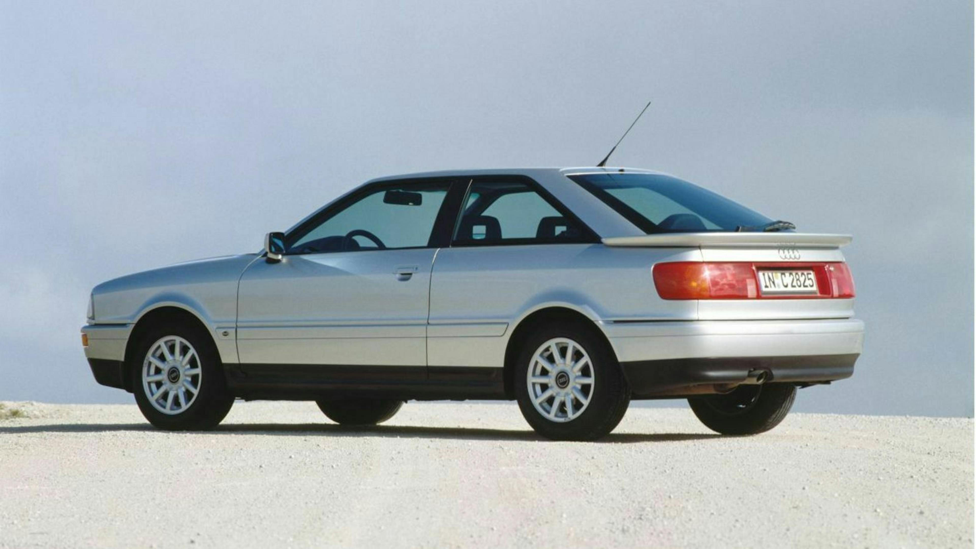 Ein silberner Audi Coupé Quattro 2.3 20V Oldtimer steht auf einem hellgrauen Steinboden.